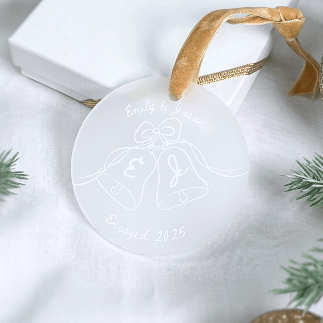 White acrylic engagement ornament with engraved bells design, personalized names and 2025 date, gold ribbon hanger