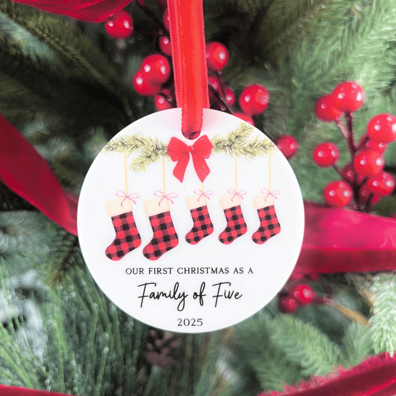 White acrylic ornament with red ribbon bow, plaid stockings illustration, and text reading "Our First Christmas as a Family of Five 2025"