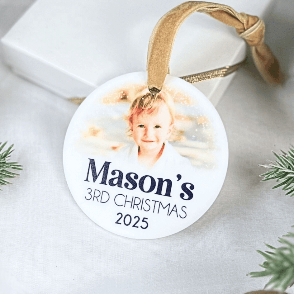 White acrylic circle ornament with child's photo, "Mason's 3RD CHRISTMAS 2025" text, and tan ribbon loop