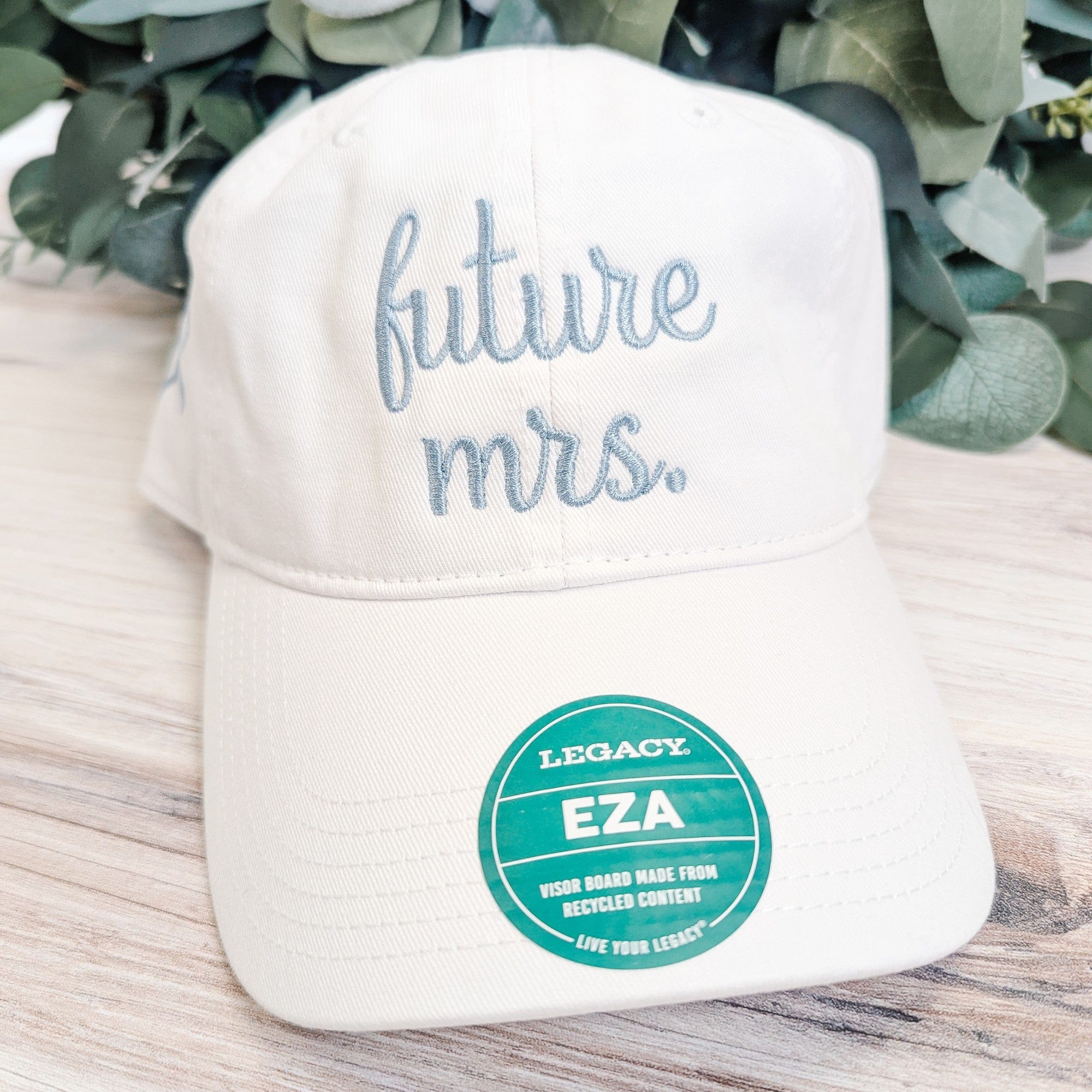 A white fabric baseball cap featuring light blue embroidery on the front, designed as a personalized bridal accessory.