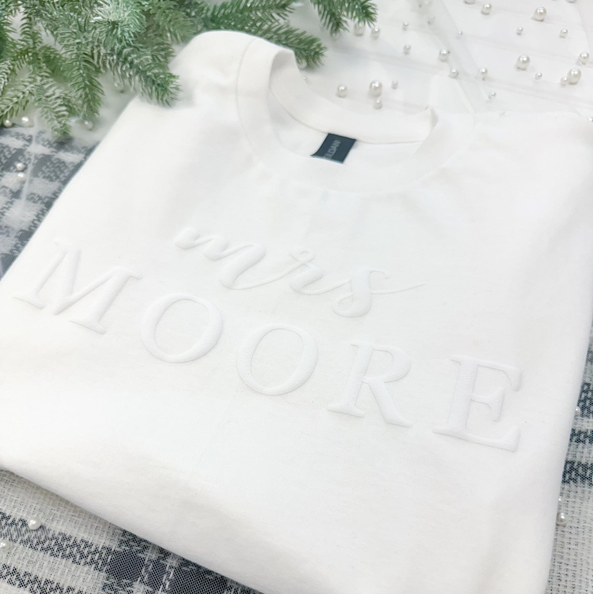 A soft white crewneck sweatshirt, designed for a bridal context, featuring elegant raised 3D lettering on the front.