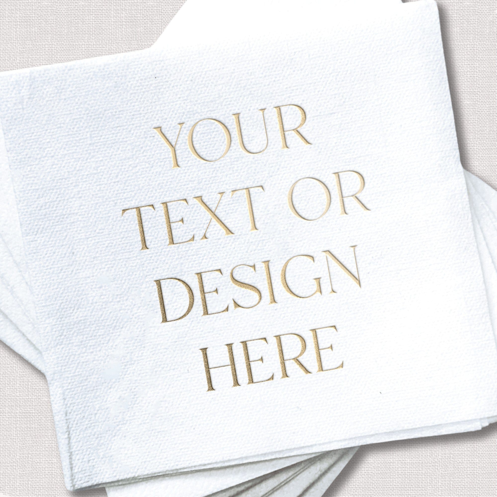 A stack of white, textured paper napkins featuring a metallic gold foil print placeholder, ideal for personalized wedding or event decor.