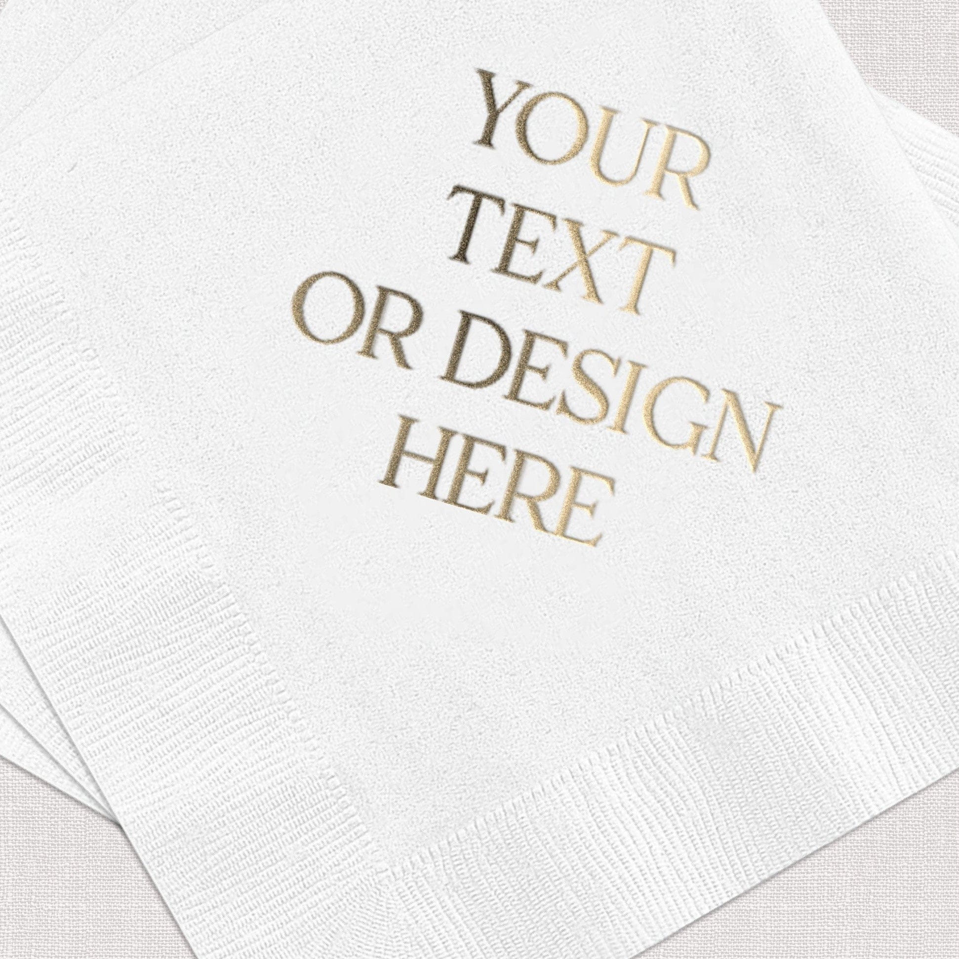 A stack of white disposable napkins features a shimmering gold foil custom text design, perfect for personalized wedding or event decor.