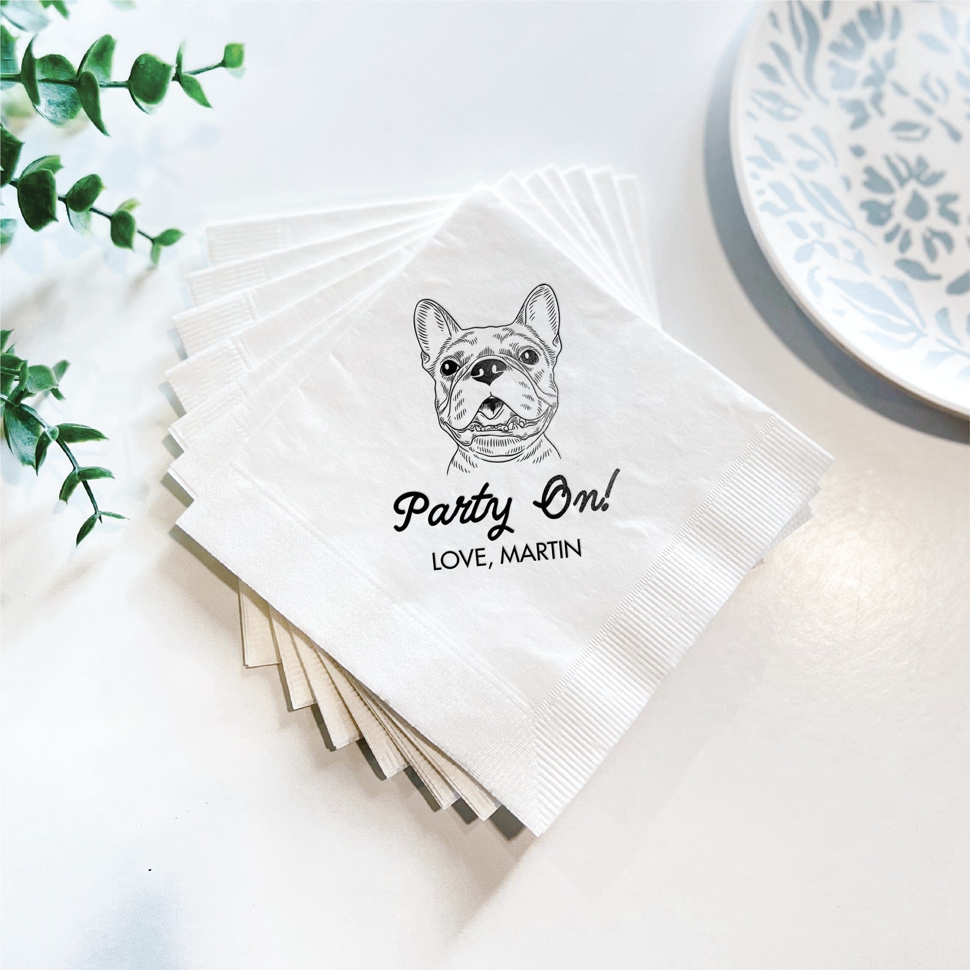 A stack of white paper napkins featuring a custom black line art illustration of a French Bulldog, perfect for a personalized party or event.