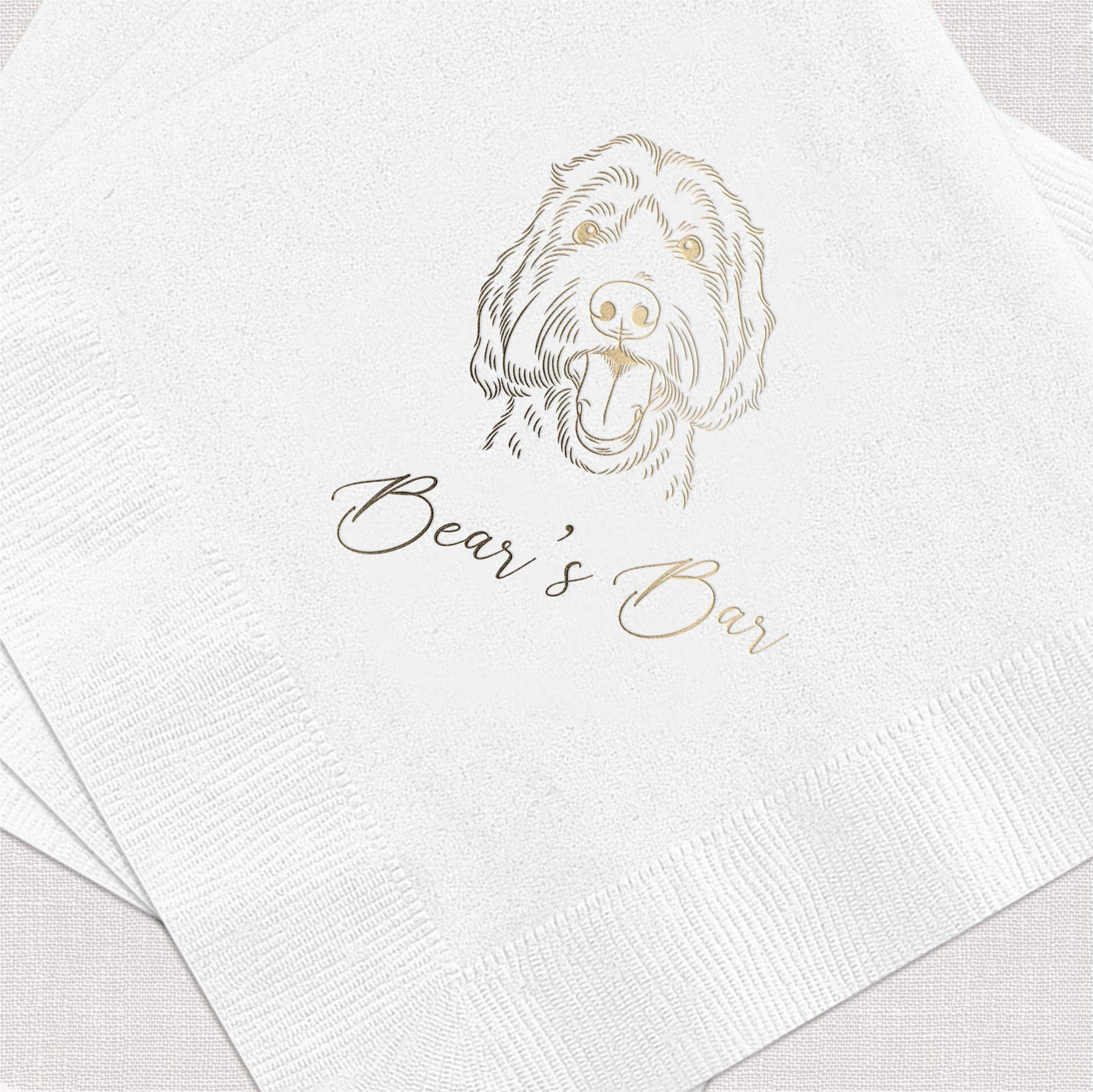A stack of white textured paper napkins featuring a custom metallic gold foil pet illustration and personalized script text, ideal for a wedding or special event bar.