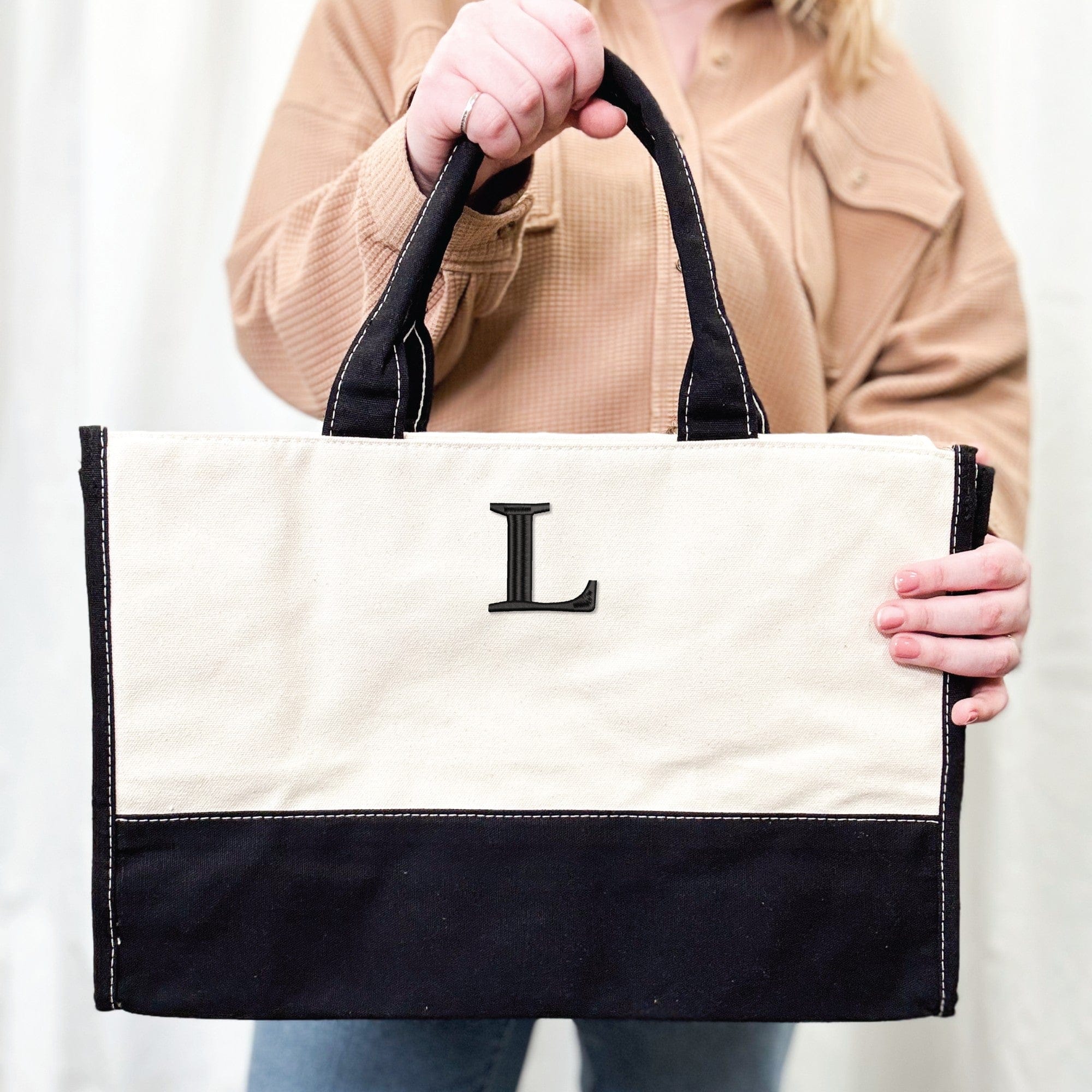 A personalized two-tone canvas tote bag featuring a natural upper section and a black lower section, black handles with white contrast stitching, ideal for event favors or daily use.