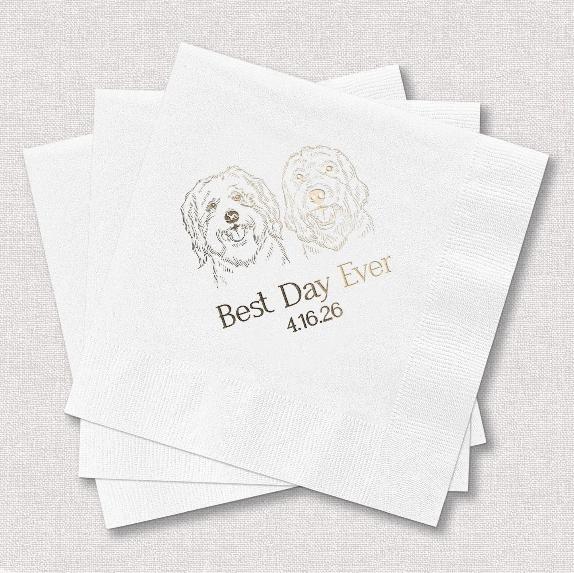 A stack of white embossed paper napkins, personalized with a shimmering gold foil illustration of two smiling dog faces, designed for a wedding or special event.