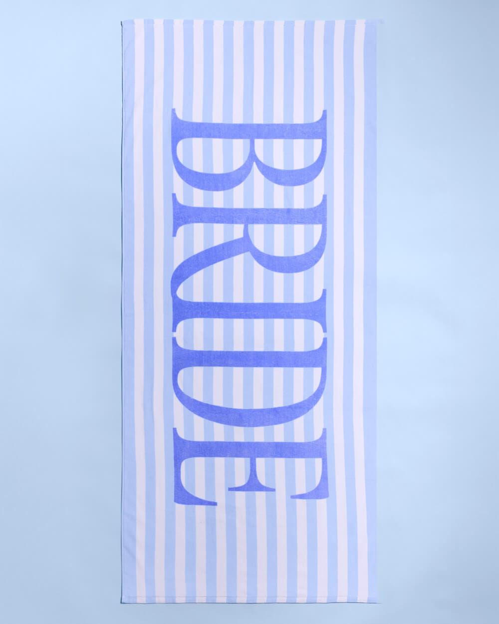 White and periwinkle striped beach towel with "BRIDE" text in bold blue lettering down the center.