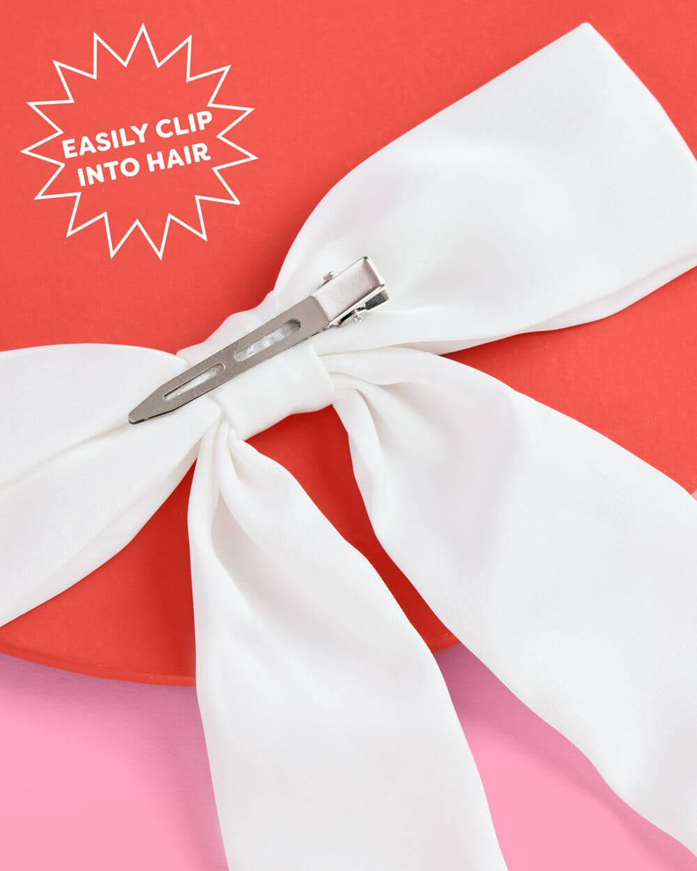 White satin bow with silver hair clip attachment on coral and pink background with "Easily Clip Into Hair" badge