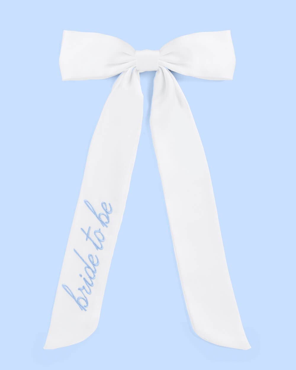Cream ribbon sash with "Bride to be" text in blue script, styled as a bow on light blue background.