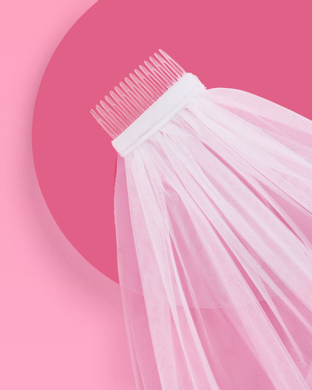Delicate white tulle veil with fine comb attachment against soft pink background