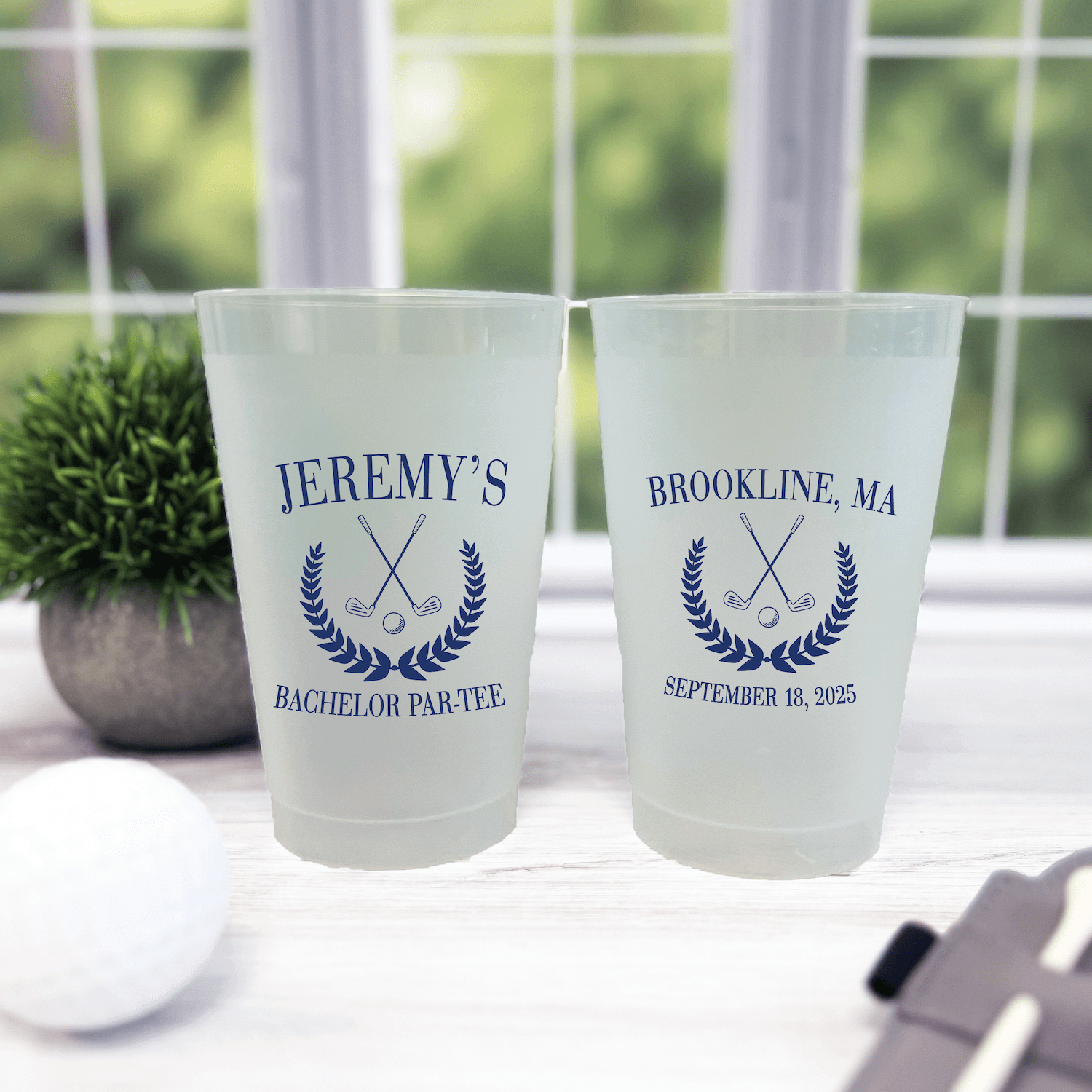 Frosted plastic cups personalized with "Jeremy's Bachelor Par-Tee" and "Brookline, MA September 18, 2025" with crossed golf clubs and laurel wreath design in blue.