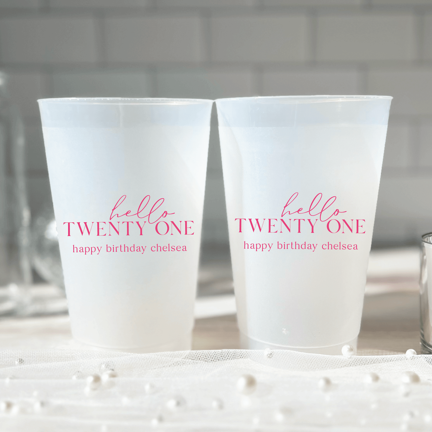 Two frosted plastic cups with pink text reading "hello TWENTY ONE" and "happy birthday chelsea"
