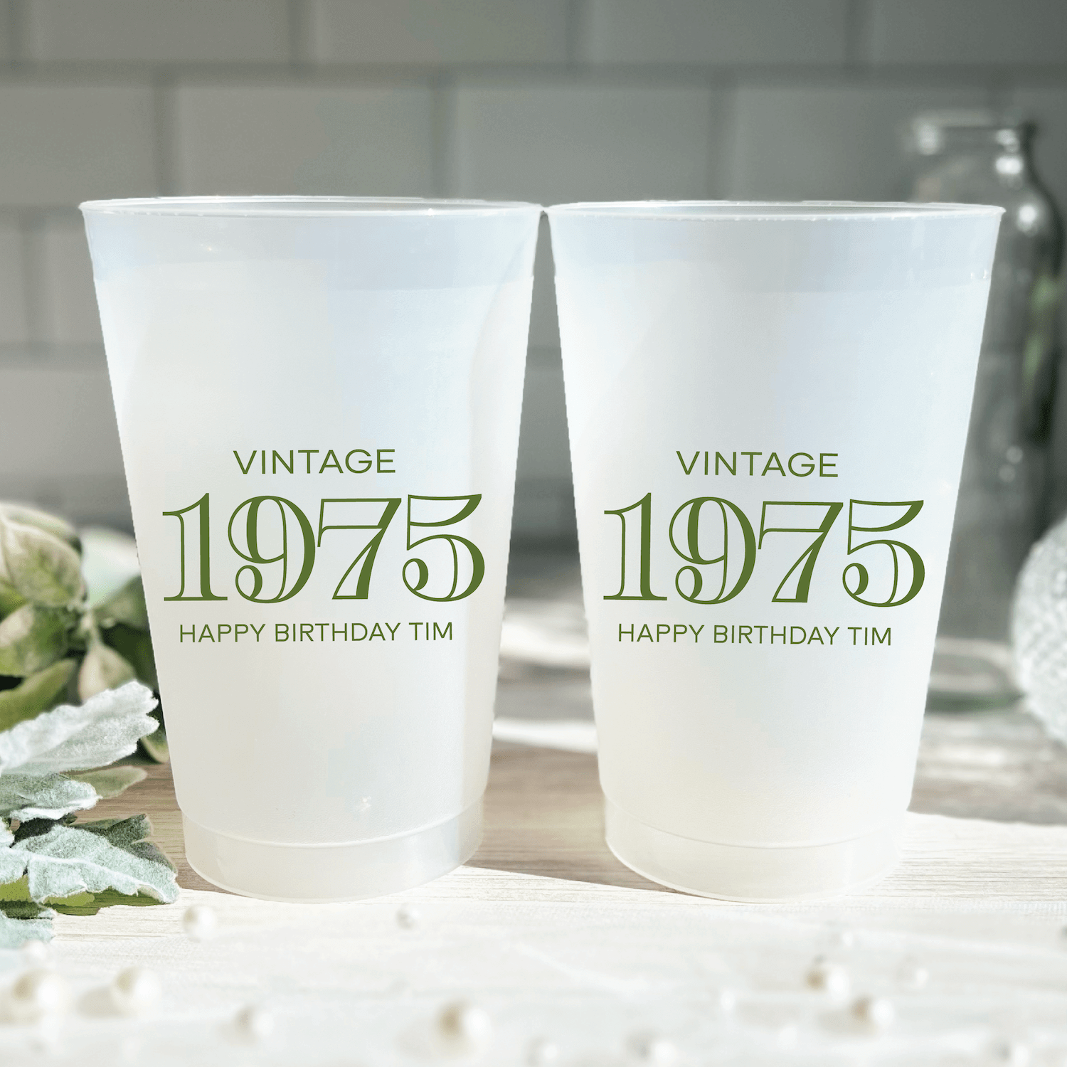 Two frosted plastic cups printed with "Vintage 1975" and "Happy Birthday Tim" in gold text