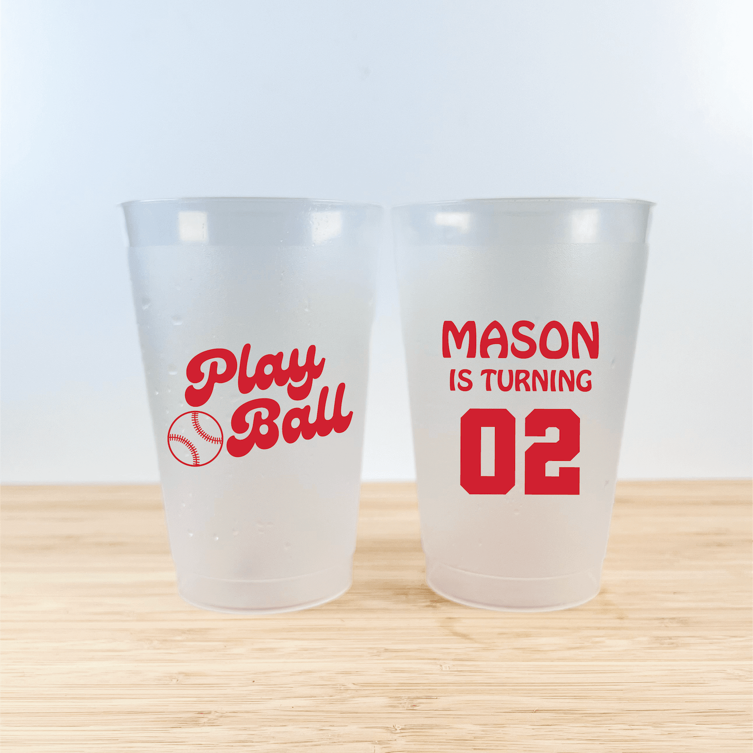 Two frosted plastic cups with red text, one reading "Play Ball" with baseball icon, the other "MASON IS TURNING 02"