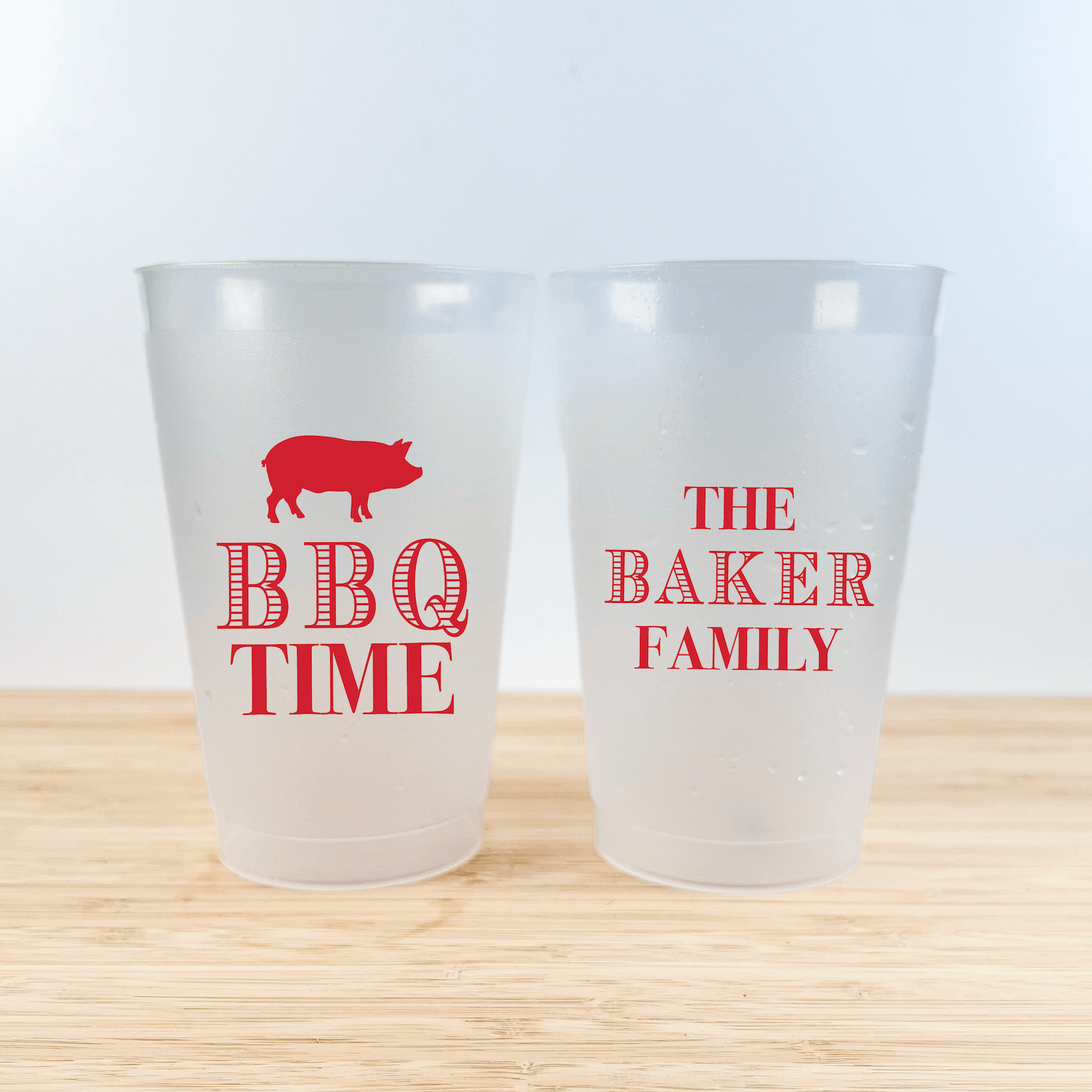Two frosted plastic cups with red text and pig graphic, one reading "BBQ TIME" with pig silhouette, the other "THE BAKER FAMILY"