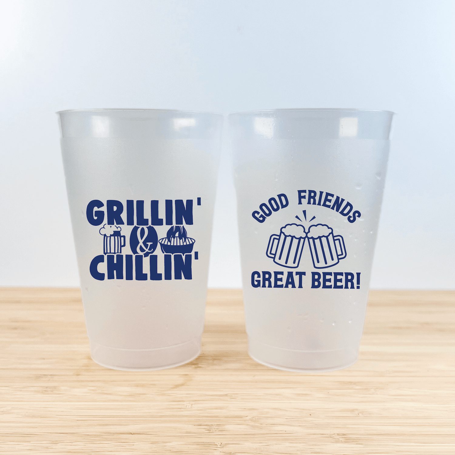 Two frosted plastic cups with navy blue designs: left cup reads "Grillin' & Chillin'" with grill and beer mug icons, right cup says "Good Friends Great Beer!" with clinking beer mugs.
