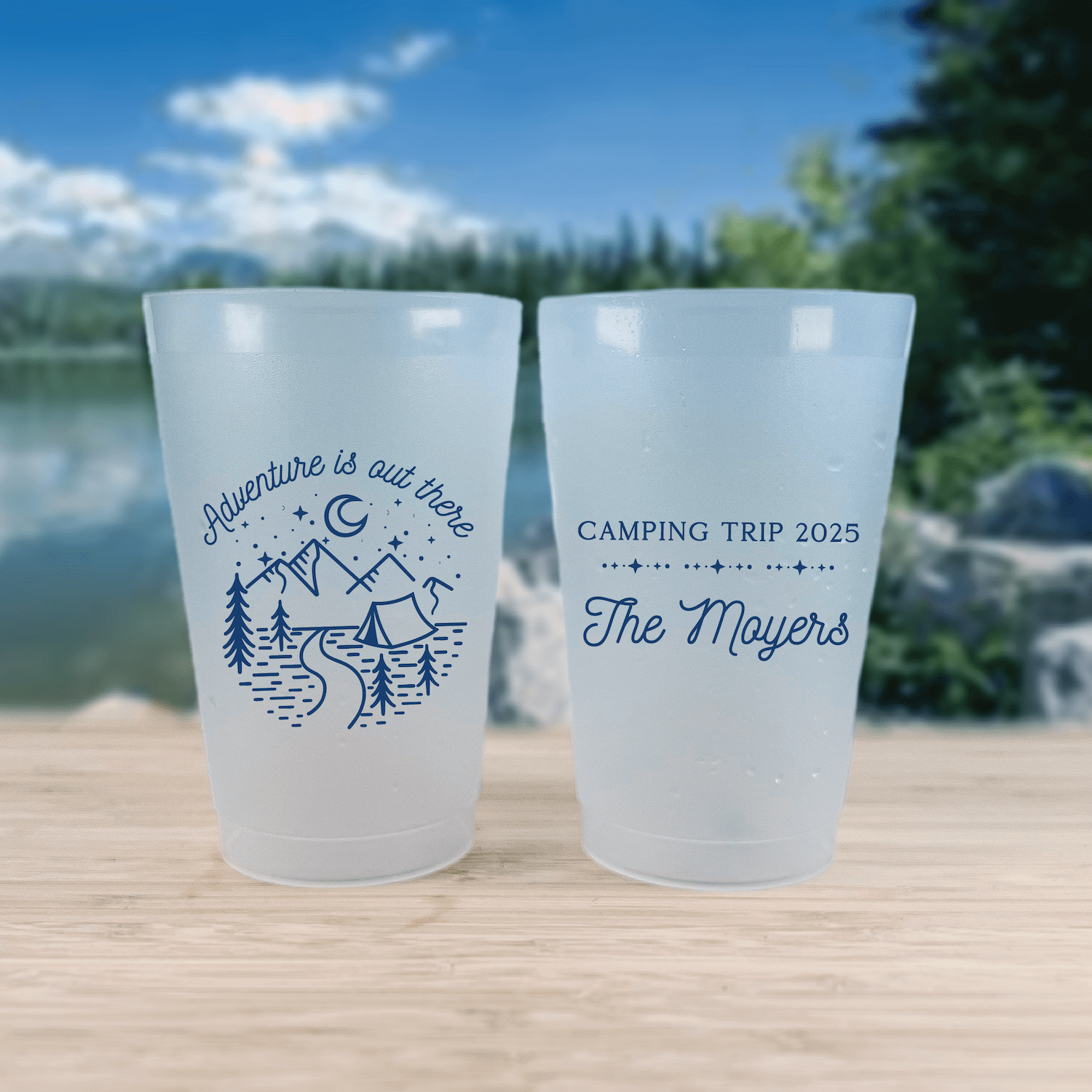 Pair of frosted shatterproof cups with camping designs. Left cup reads "Adventure is out there" with mountain and tent illustration. Right cup says "Camping Trip 2025 The Moyers" in blue text.