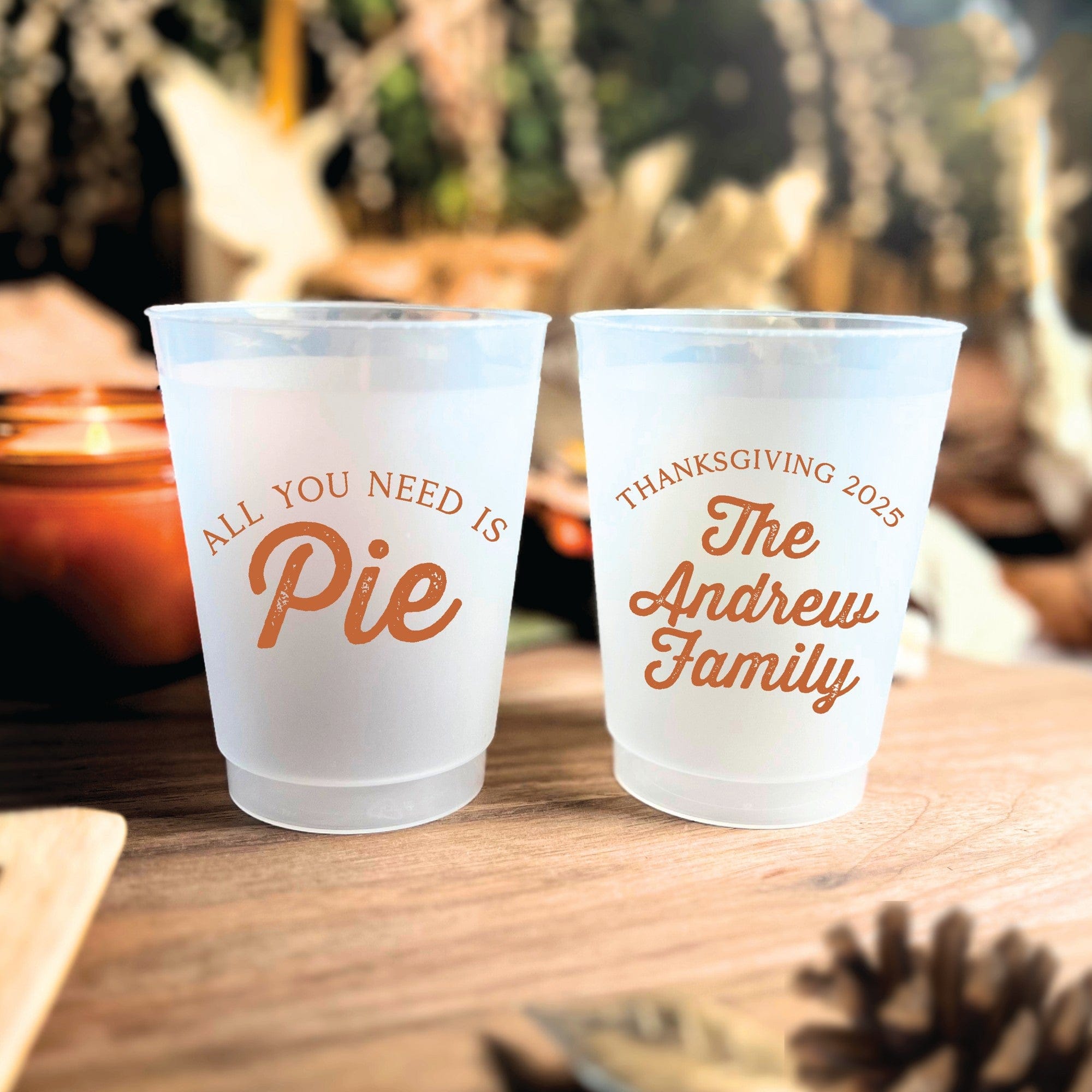 Two frosted white plastic cups with custom orange autumnal designs, ideal for a personalized Thanksgiving celebration or fall event.