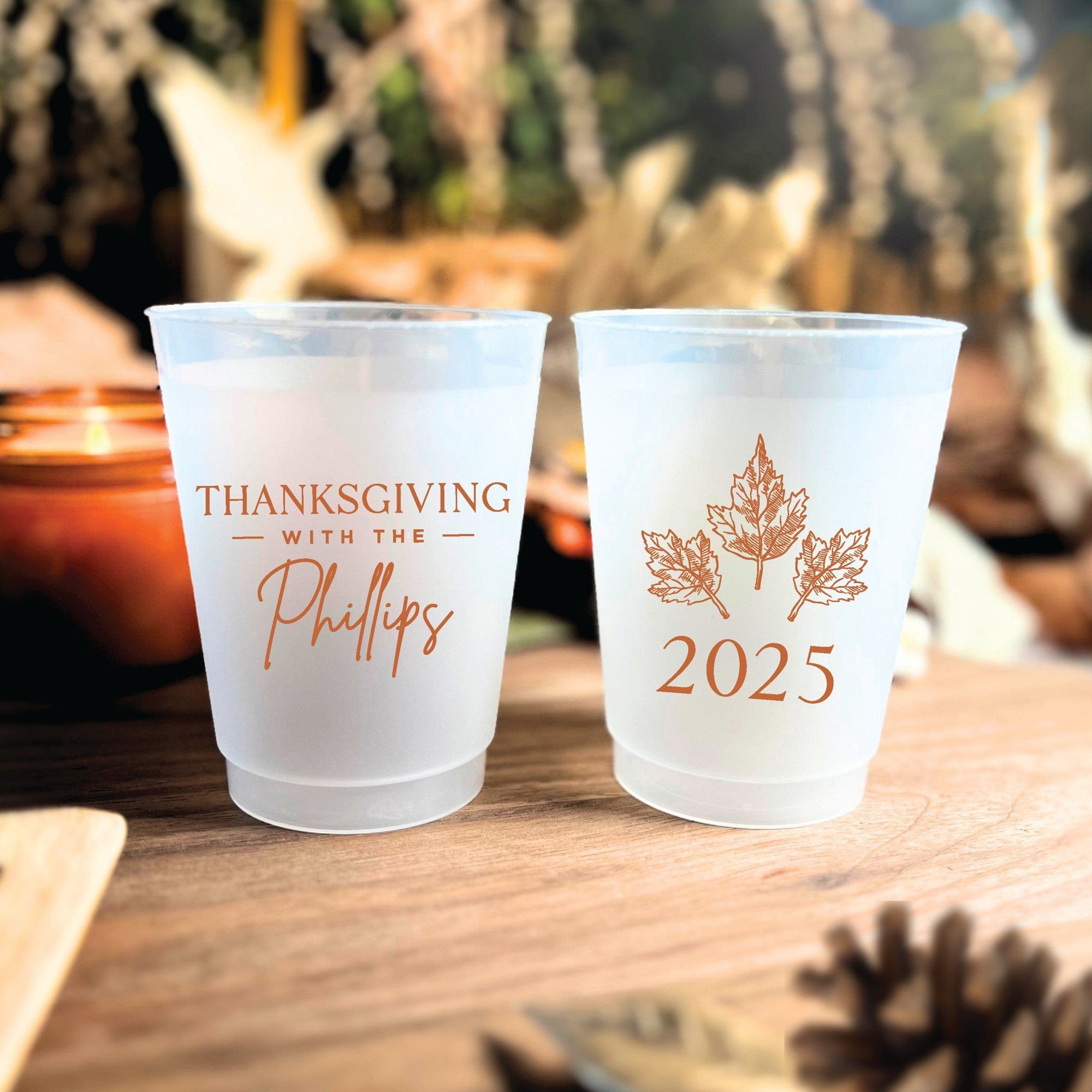 Two personalized frosted plastic cups are adorned with rustic autumn leaf graphics and festive event details, ideal for fall celebrations.