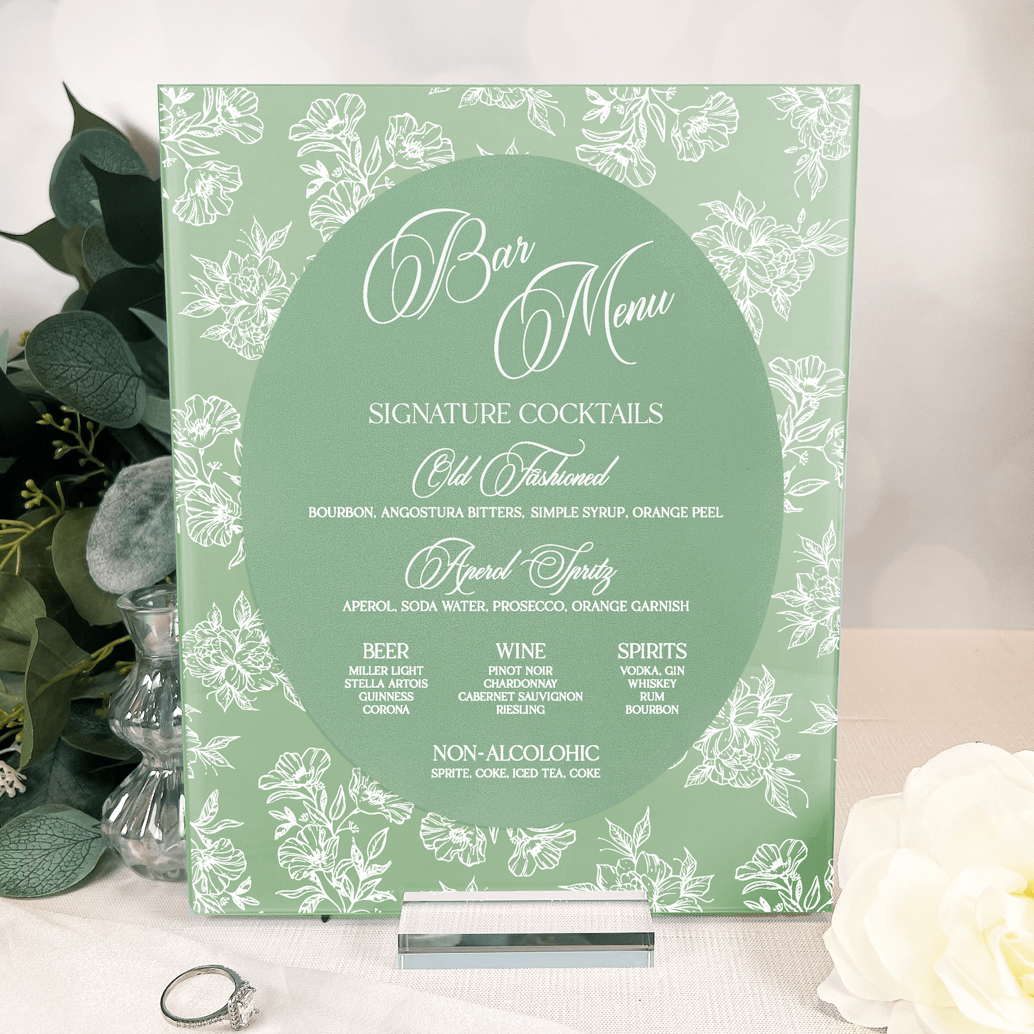 Sage green bar menu sign with white toile floral pattern featuring signature cocktails and drink options for wedding reception.