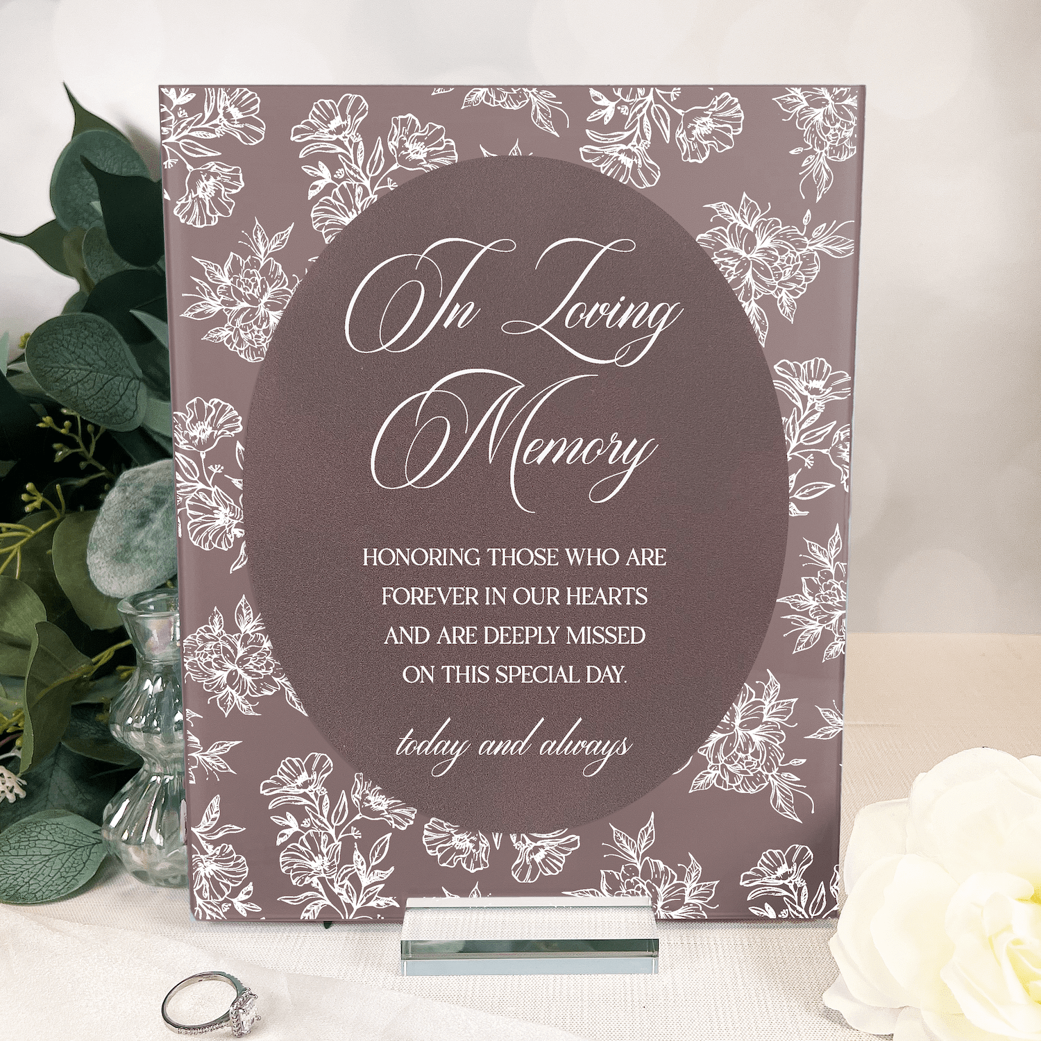 Mauve acrylic sign with white toile floral border and "In Loving Memory" script text, displayed with greenery and white flowers
