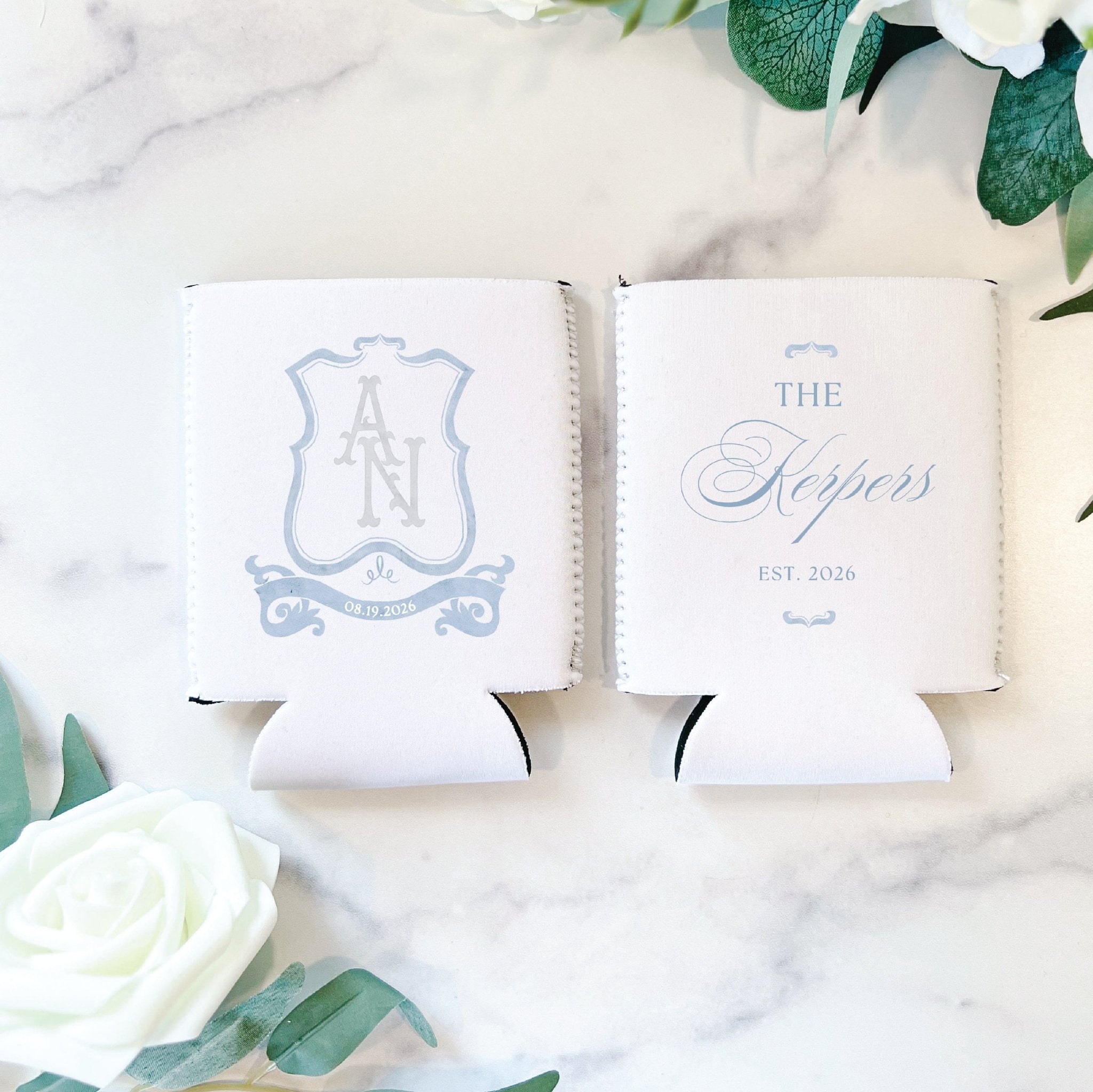 Pair of white can coolers with light blue monogram crest and "The Hoppers EST 2024" wedding design
