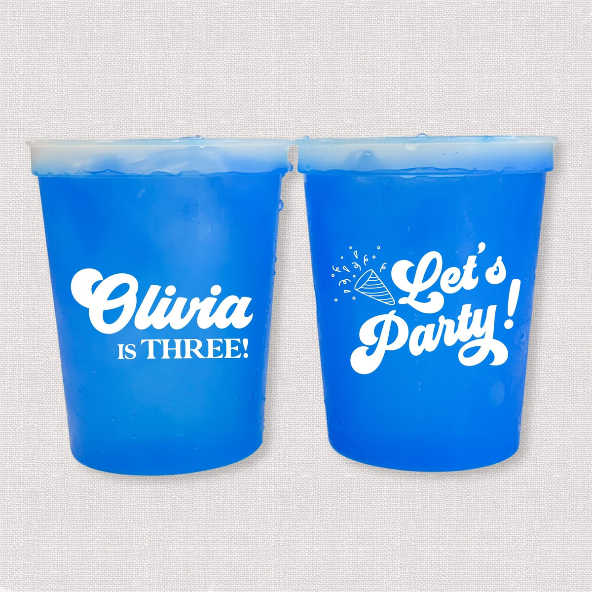 Blue color changing kids birthday stadium cups with Olivia is Three name and Let's Party design