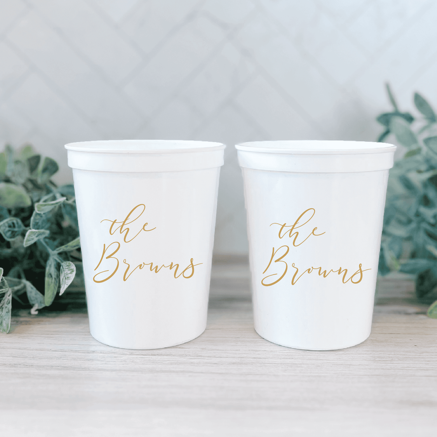 Two white stadium cups with gold foil "the Browns" script personalization displayed side by side