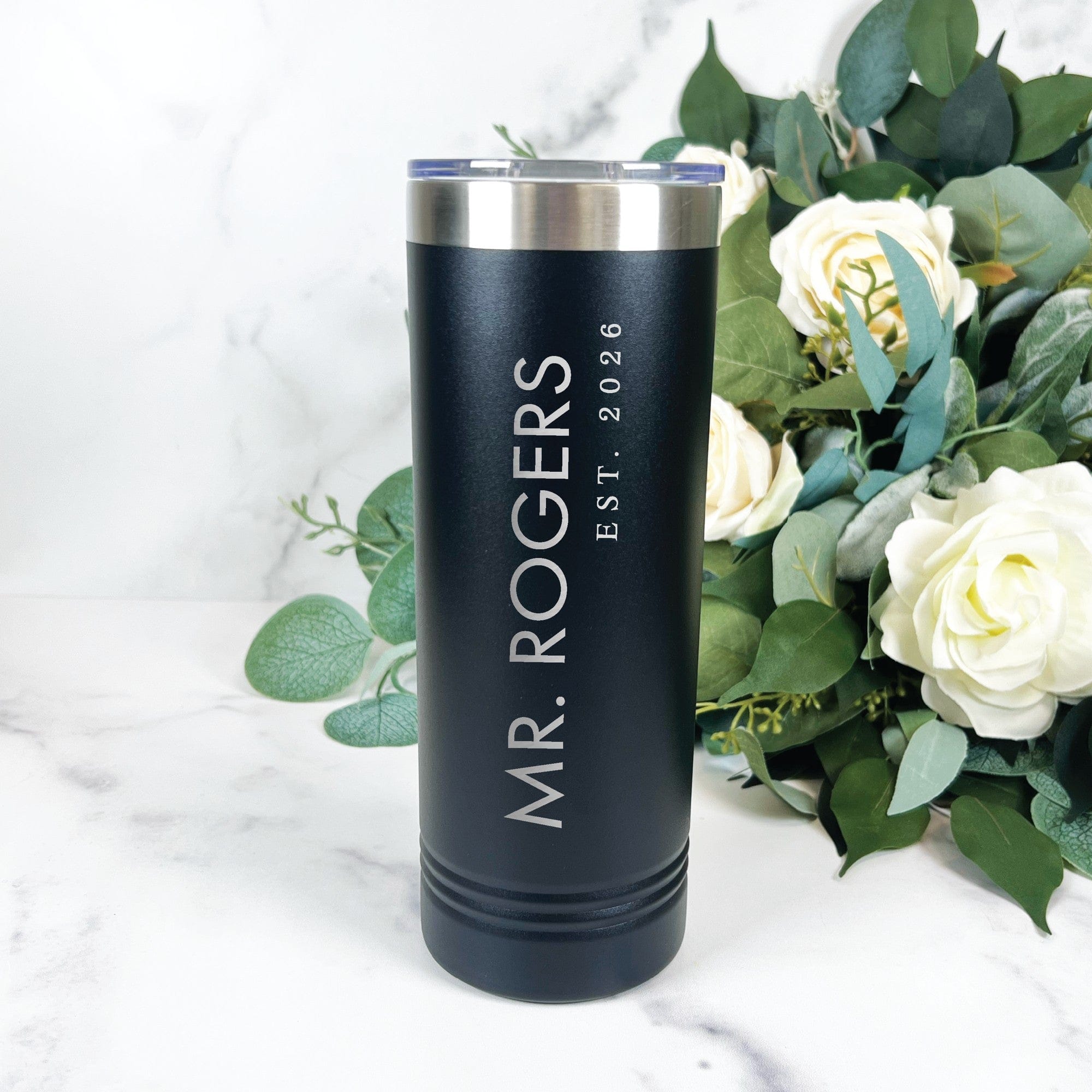 A black insulated stainless steel tumbler with a silver rim and clear lid, featuring personalized engraving, perfect as a wedding party gift.
