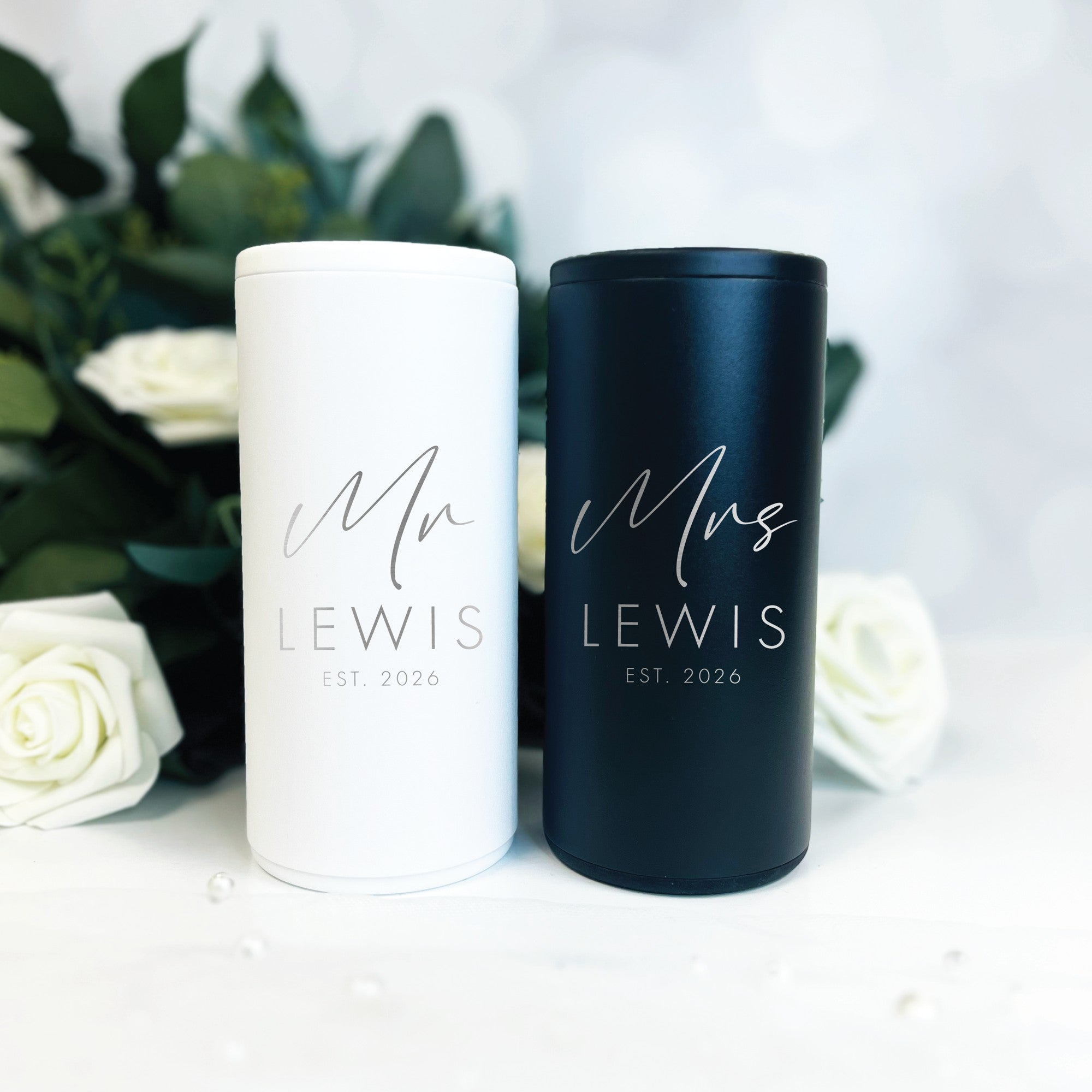 A pair of sleek white and black insulated slim can coolers feature silver personalized designs, ideal for keeping beverages cold at wedding or bridal events.