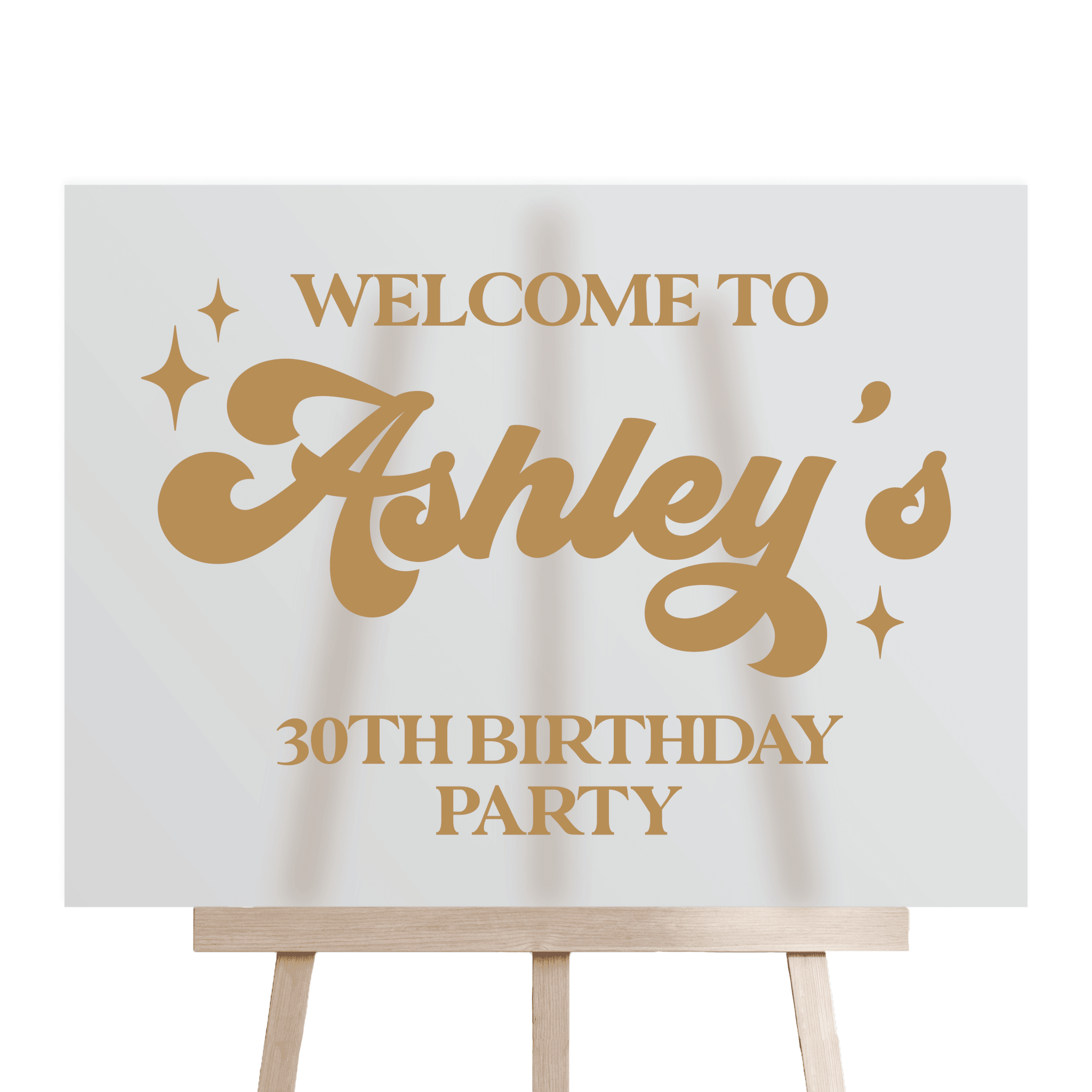 White acrylic welcome sign with gold retro lettering reading "Welcome to Ashley's 30th Birthday Party" with decorative stars, displayed on a wooden easel.