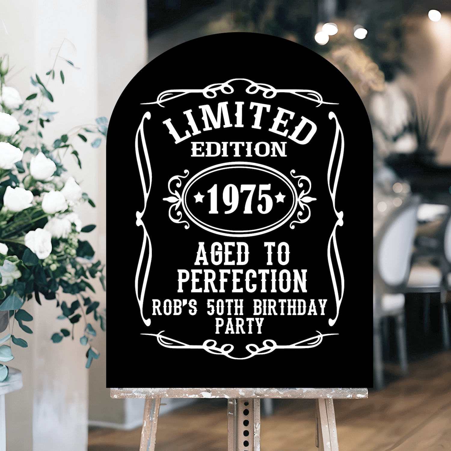 Black arch-top welcome sign with white vintage-style text reading "Limited Edition 1975 Aged to Perfection Rob's 50th Birthday Party"