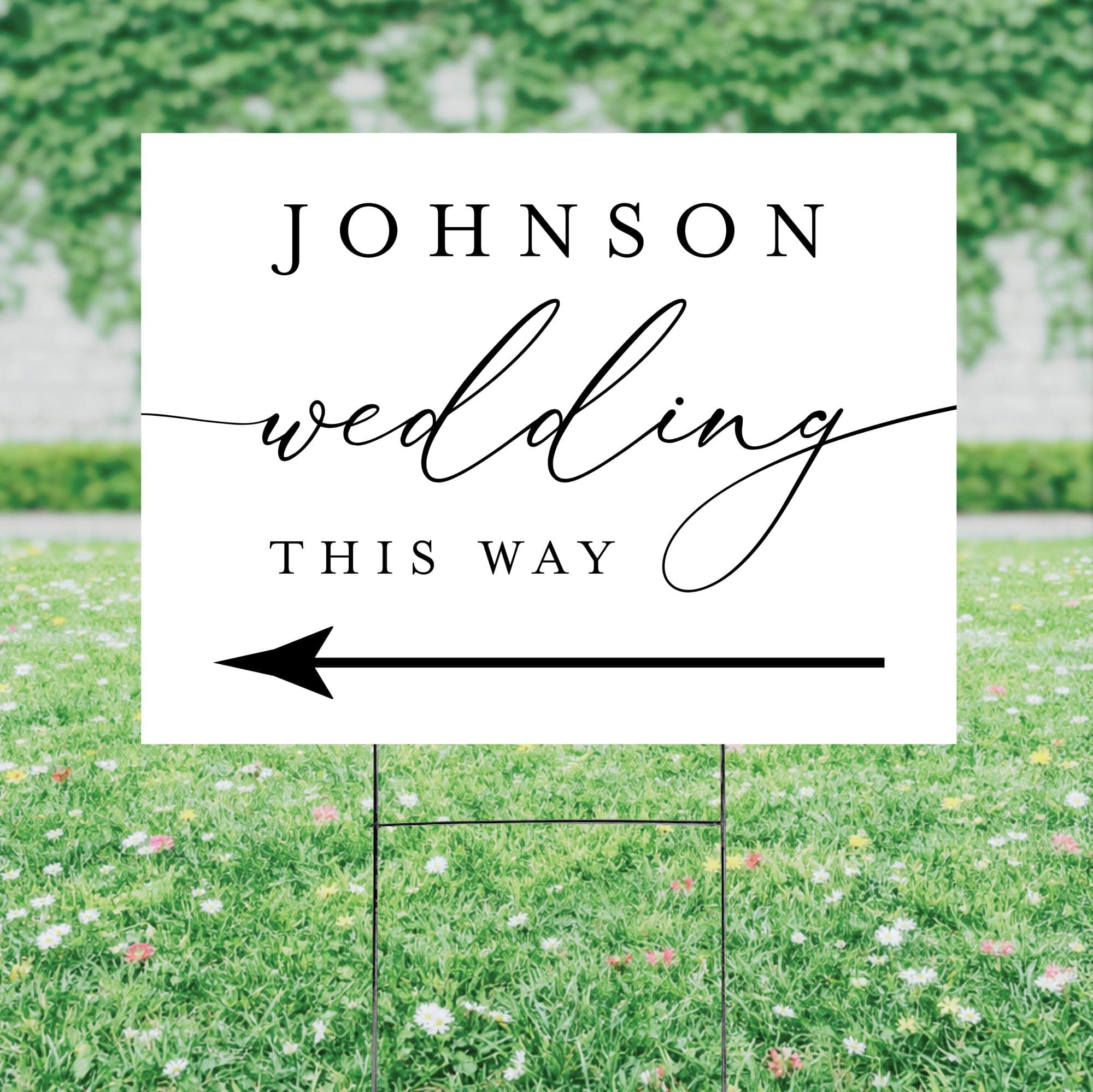 A white corrugated plastic yard sign with a metal H-stake features black elegant script and bold text, along with a prominent left-pointing arrow, designed to direct guests at a wedding.
