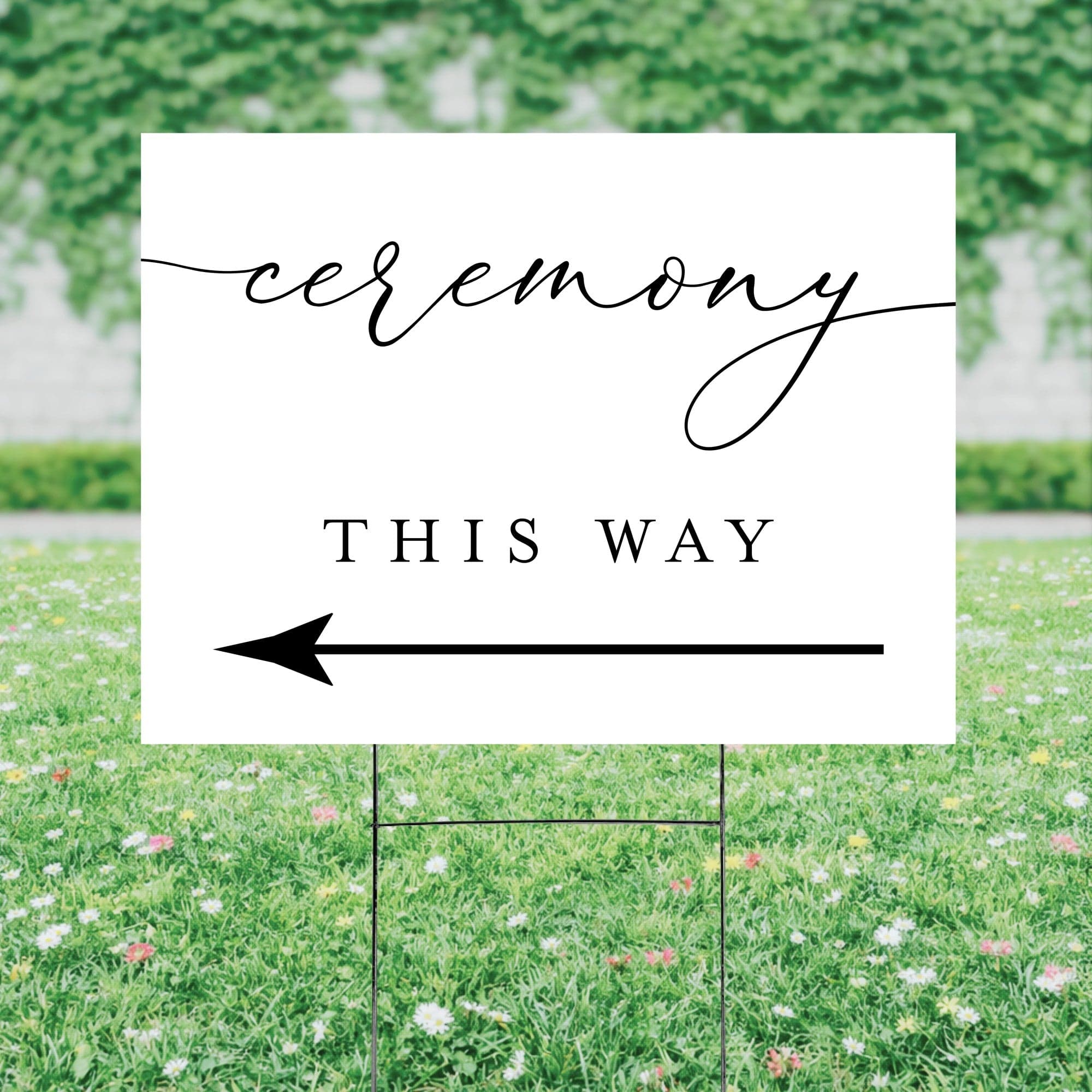 A white personalized wedding directional yard sign with a black arrow and elegant script typography is displayed on a metal H-stake, designed to guide guests to the event.