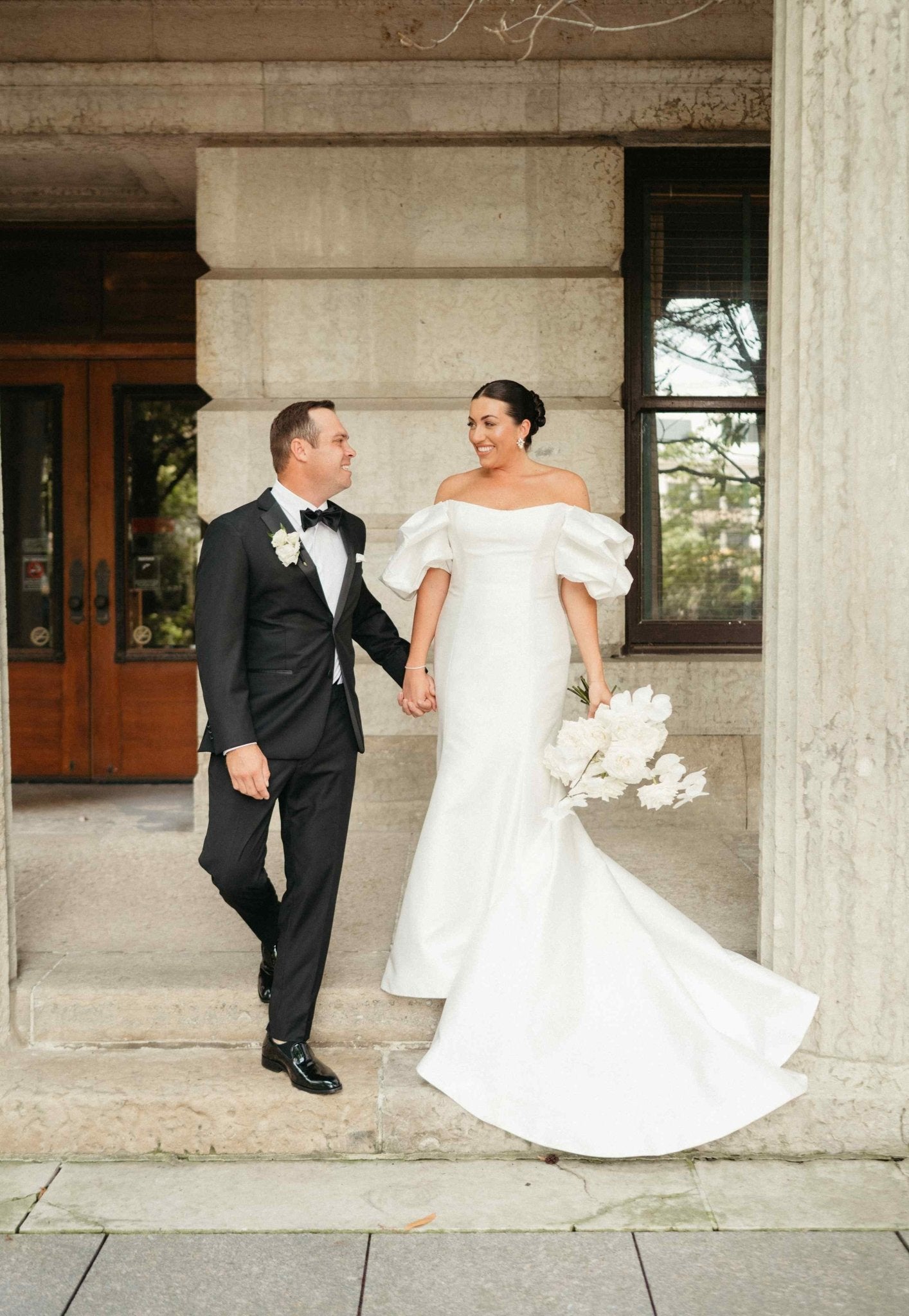 A wedding couple holding hands, captured in a romantic lifestyle moment at their celebration.