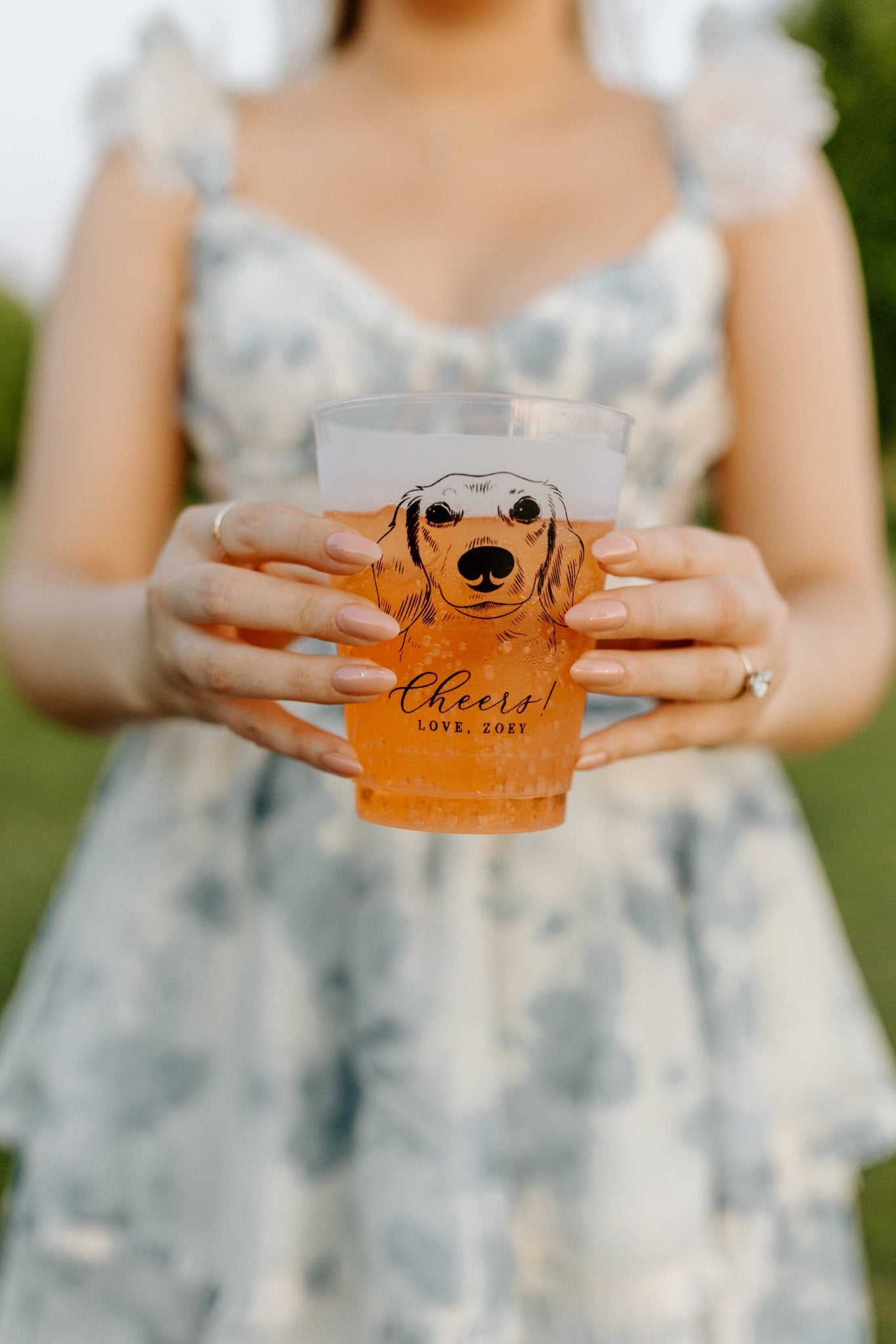 A person holds a custom frosted plastic cup featuring a dog illustration and Cheers! text, ideal for celebrations and parties.