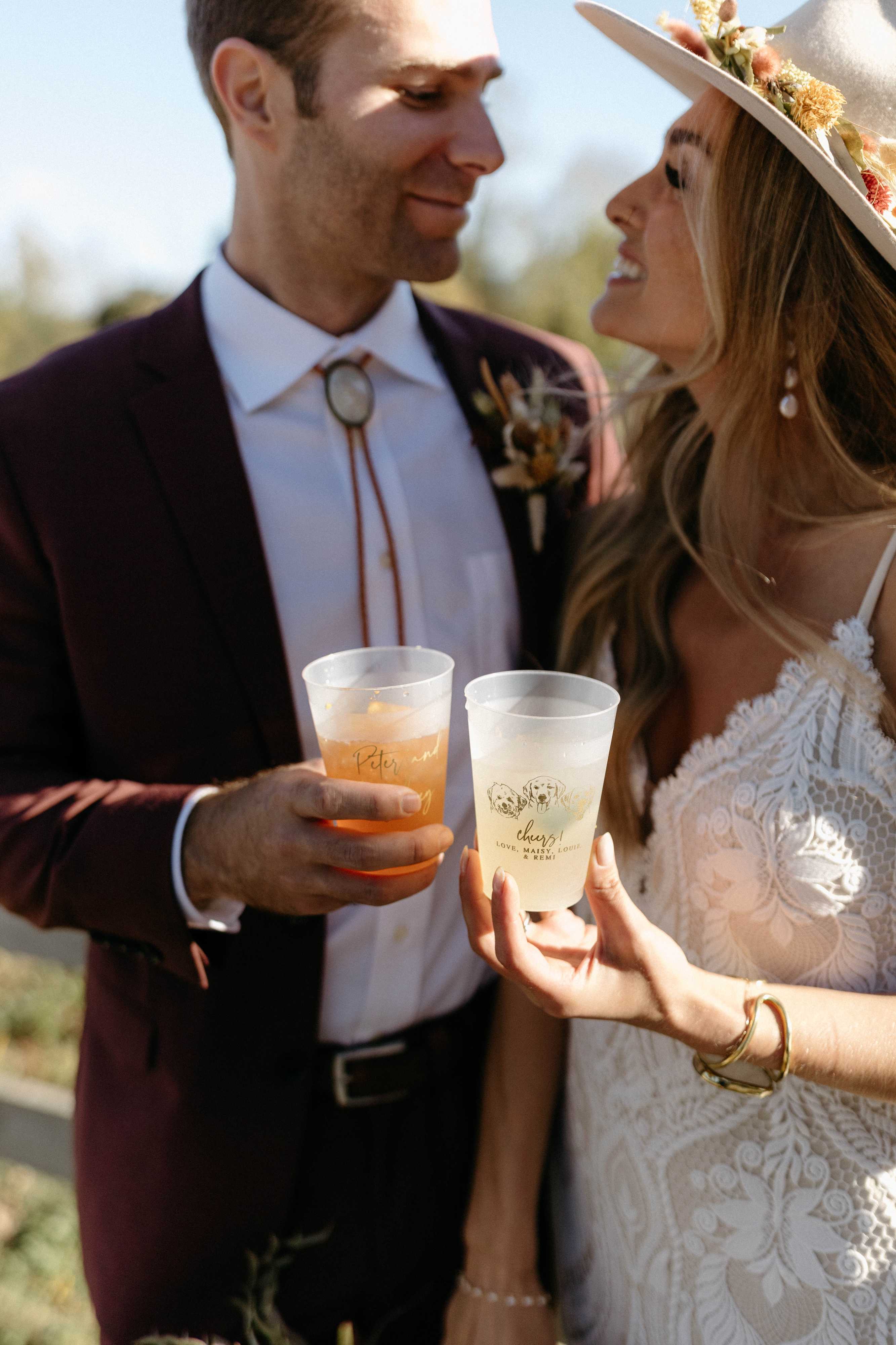 Personalized frosted plastic wedding cups featuring a custom dog illustration, held at a wedding reception.