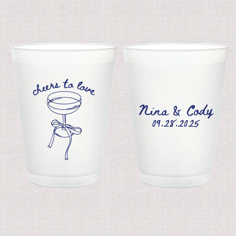 Pair of frosted plastic cups with blue script text reading "cheers to love" and a cocktail illustration on one side, personalized names and wedding date on the other