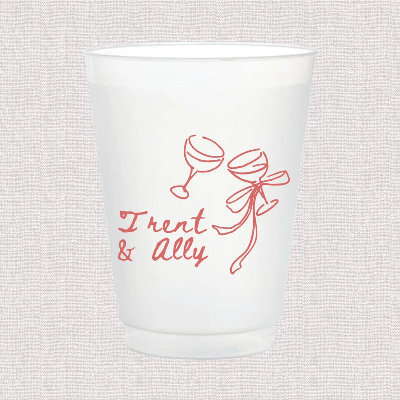 White frosted plastic cup with pink line art of two champagne glasses and ribbon, personalized with "Trent & ally" in script text.