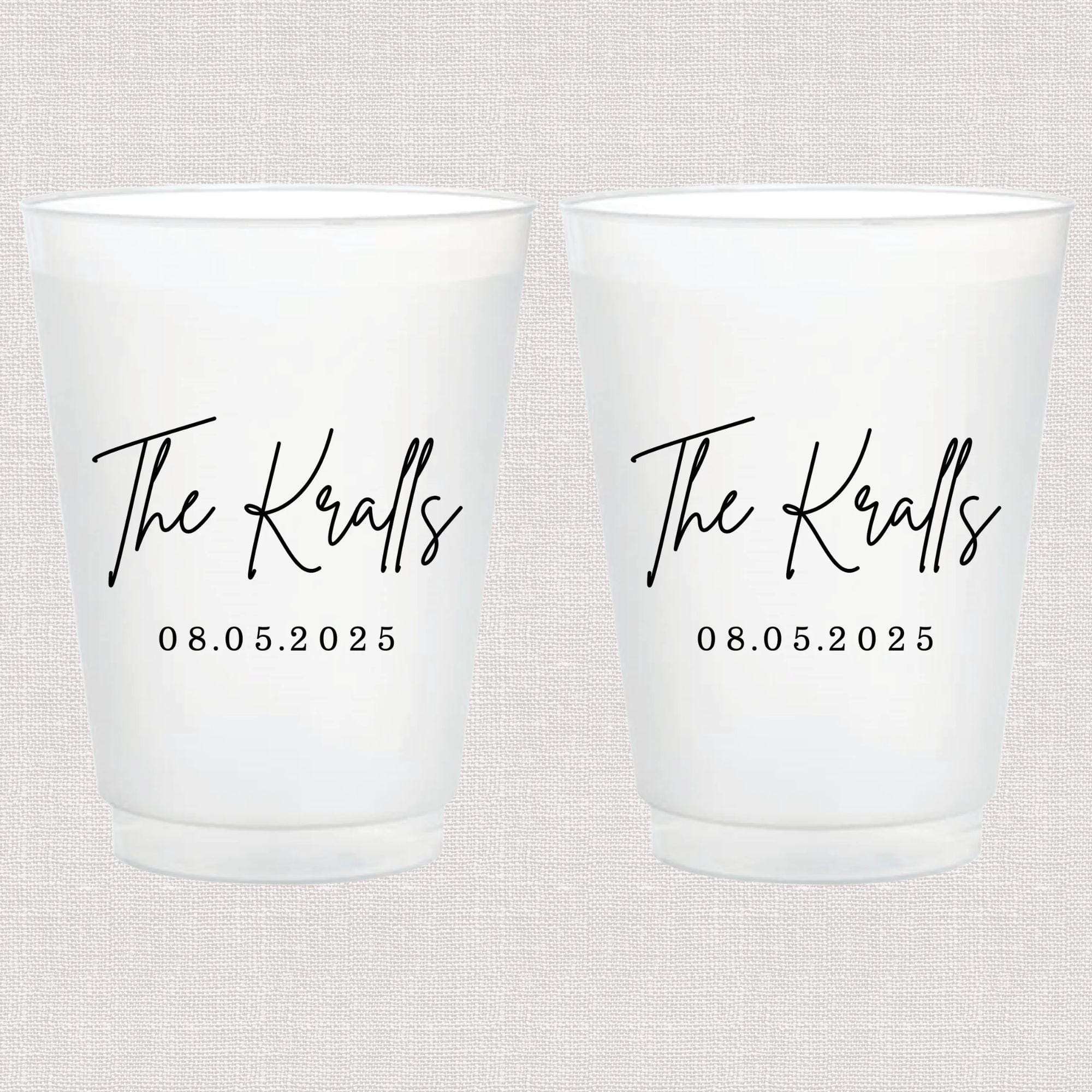 Pair of frosted white cups personalized with "The Kralls" and wedding date 08.05.2025 in black script and numbers