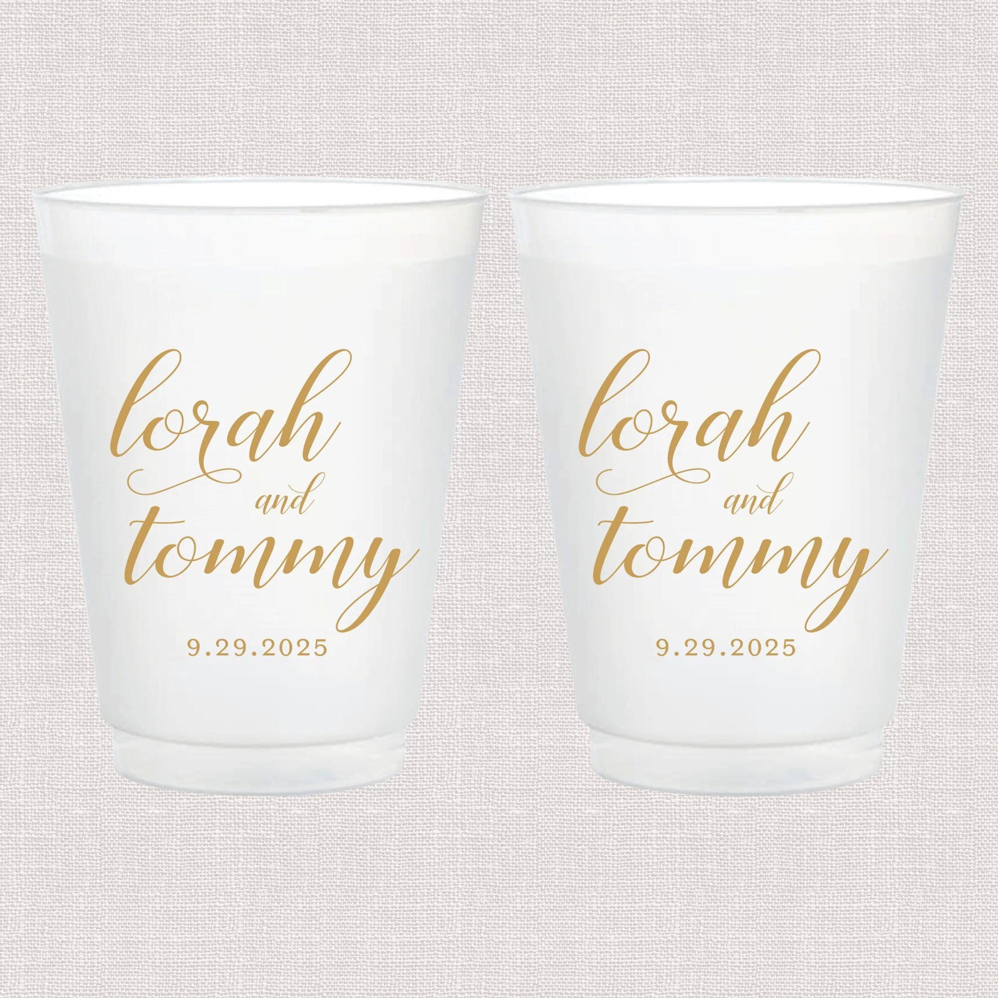 Pair of frosted white shatterproof cups with gold script text reading "lorah and tommy" and wedding date "9.29.2025"