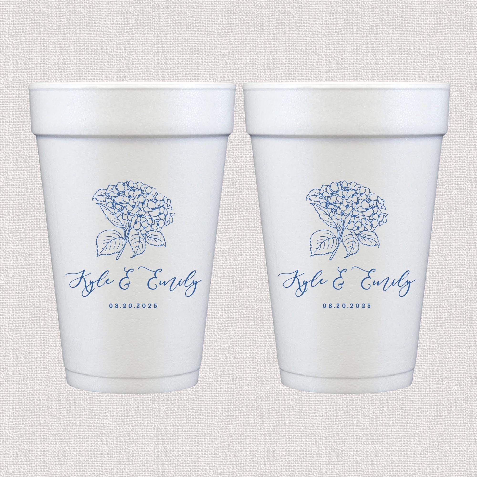 Two white foam cups with blue hydrangea flower design and personalized names and wedding date printed below the flower.