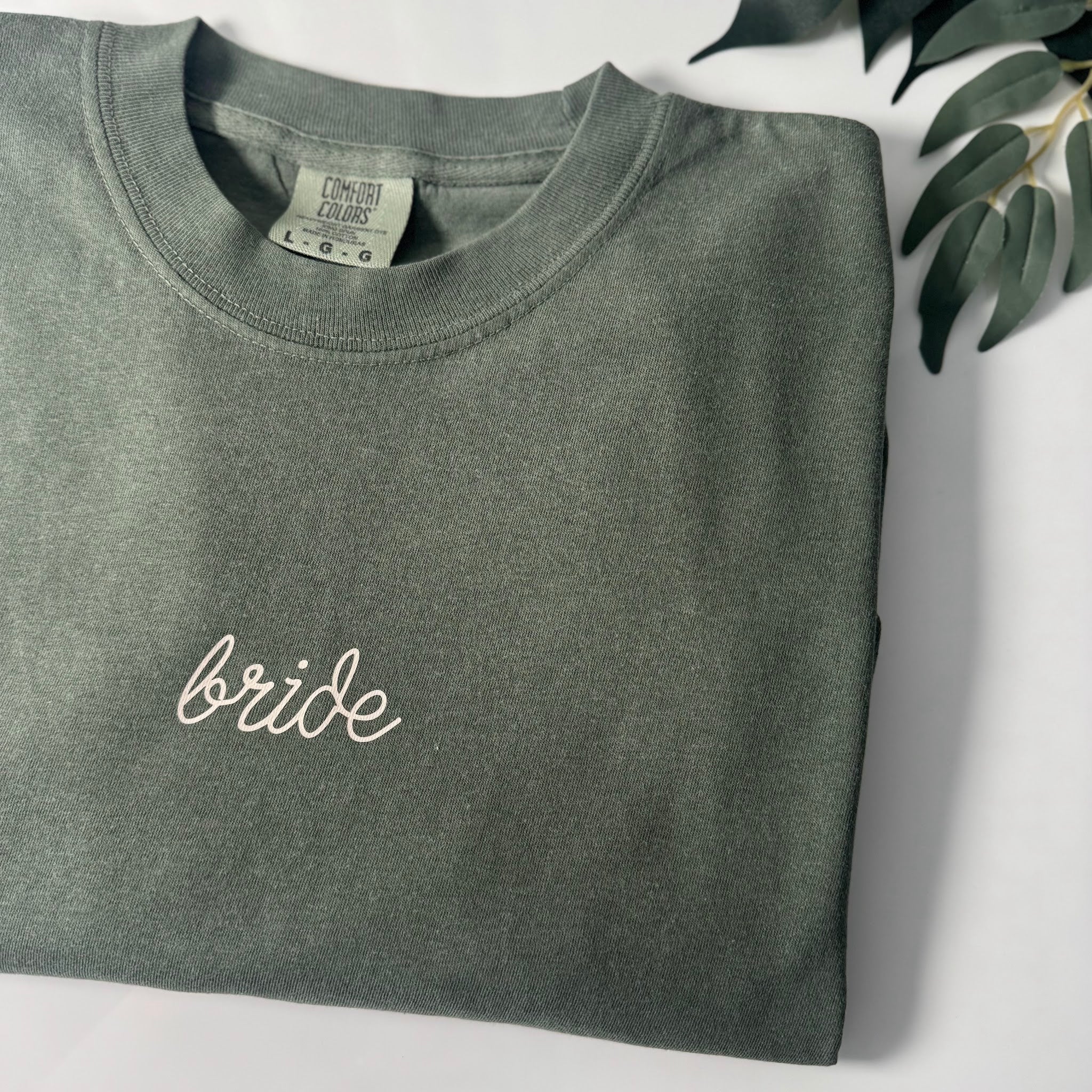 Embroidered Bride shirt in hunter green Comfort Colors 1717, styled flat lay