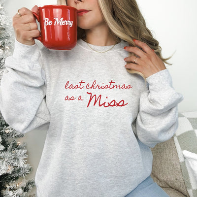 A light grey long-sleeved sweatshirt with a custom red script design, perfect for celebrating a special pre-wedding milestone during the holiday season.