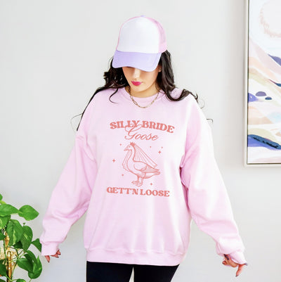 A light pink crewneck sweatshirt featuring a graphic of a goose wearing a bridal veil and crown, designed for a bridal event.