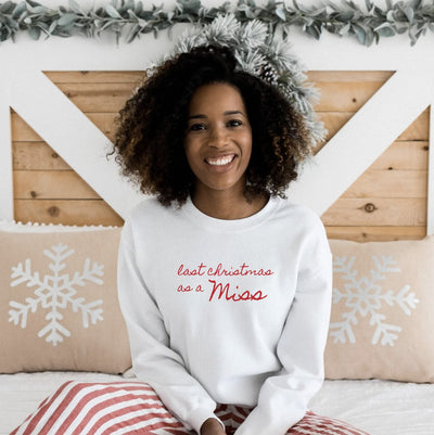 A white crewneck sweatshirt with red custom lettering, perfect for a bride-to-be celebrating a holiday season before marriage.