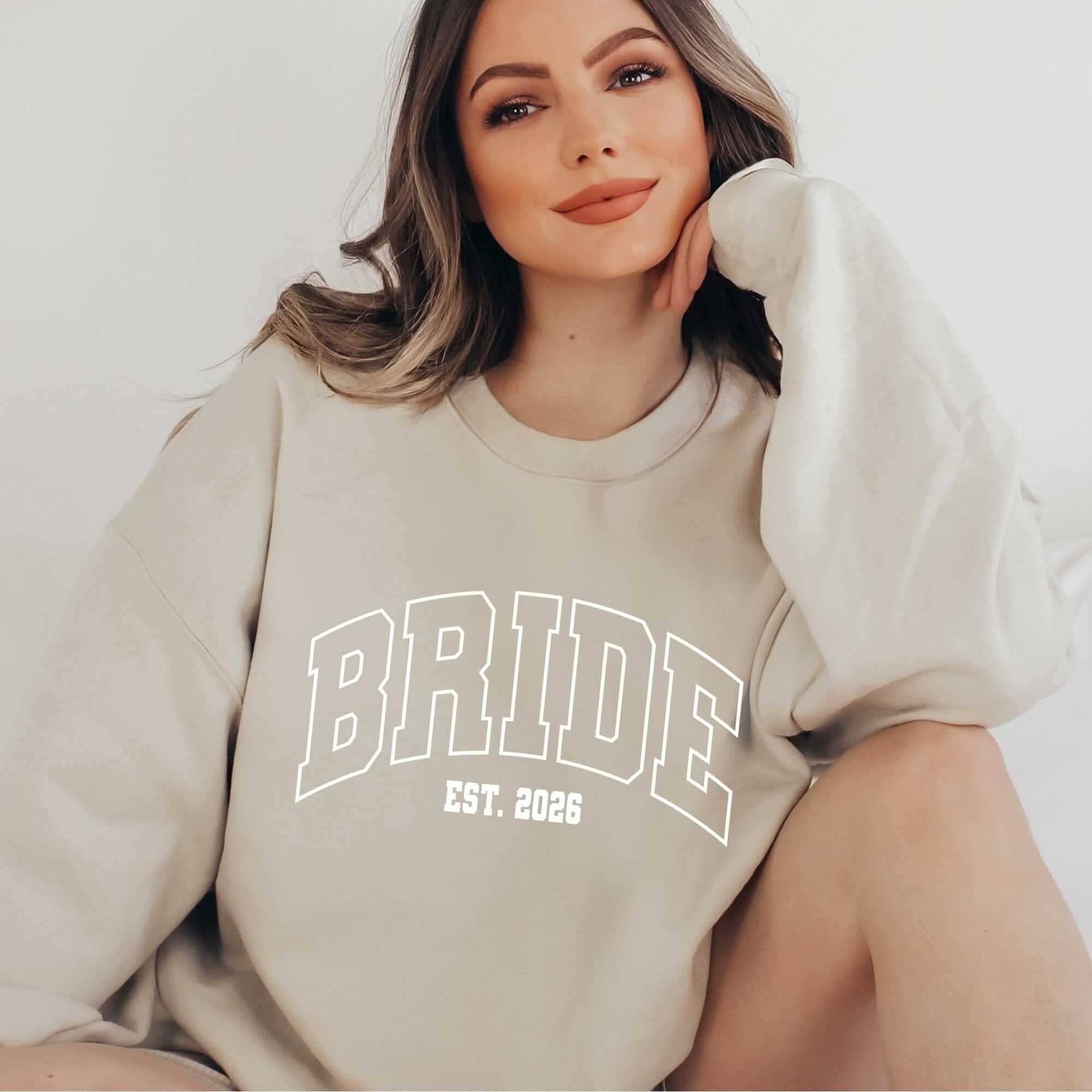 An oversized light beige crewneck sweatshirt made from soft fabric, perfect for celebrating an engagement or pre-wedding events.
