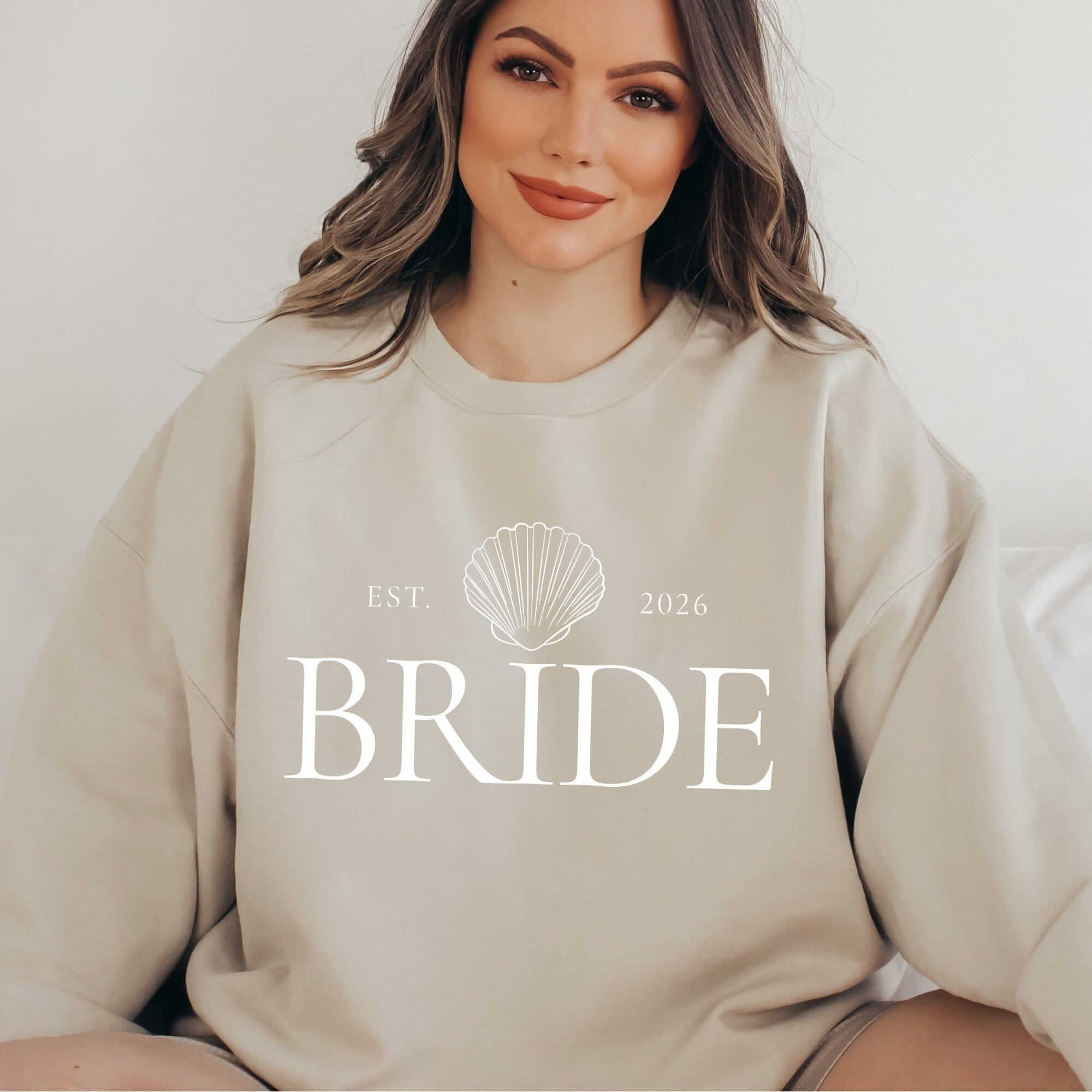 A comfortable beige bridal crewneck sweatshirt featuring a white seashell graphic design.