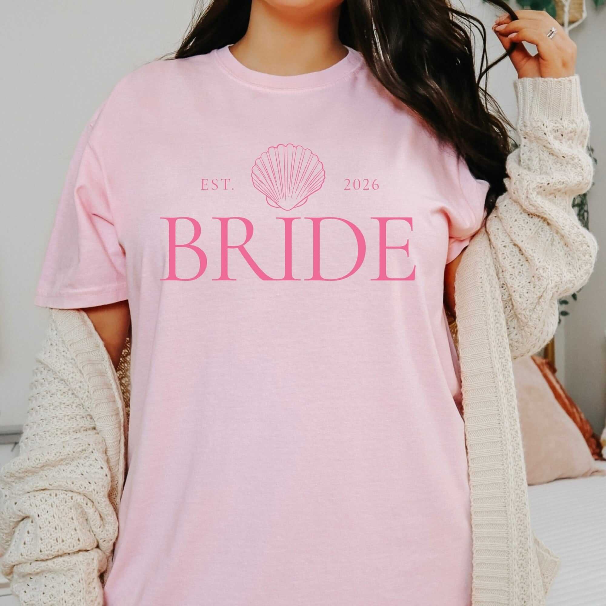 A light pink cotton t-shirt featuring a darker pink seashell graphic, perfect for a bridal event.